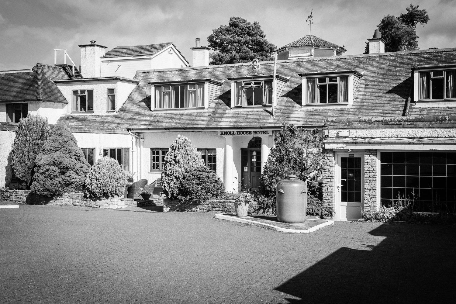 Black and white panoramic view of a mid-century modern residential building with multiple dormer windows and landscaping.