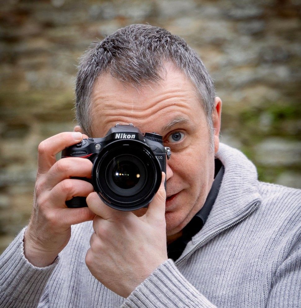 Photographer in gray sweater taking photos with Nikon camera shown in sequence of four similar shots.