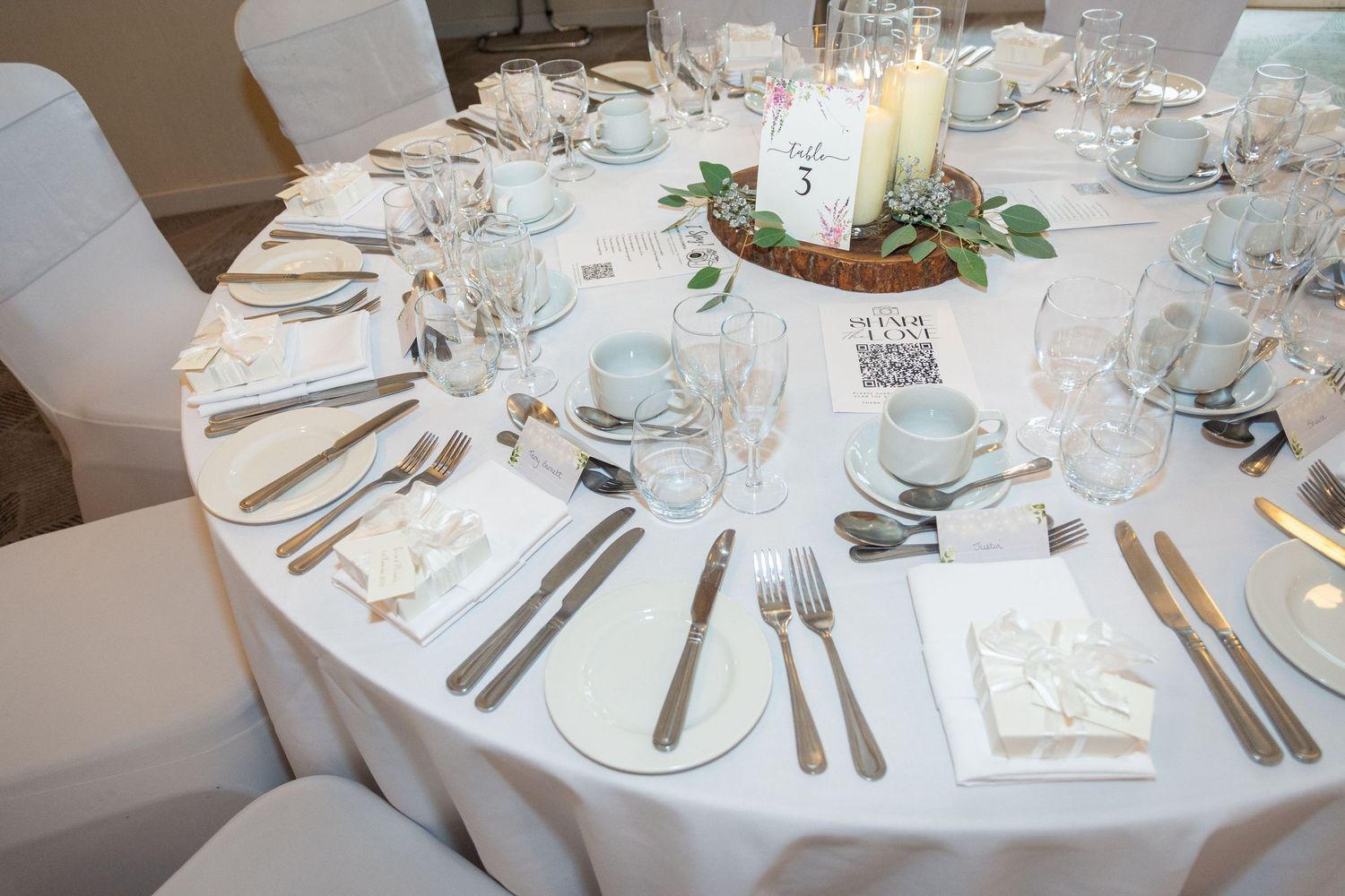 Elegant white wedding table setting with candles and floral centerpiece.