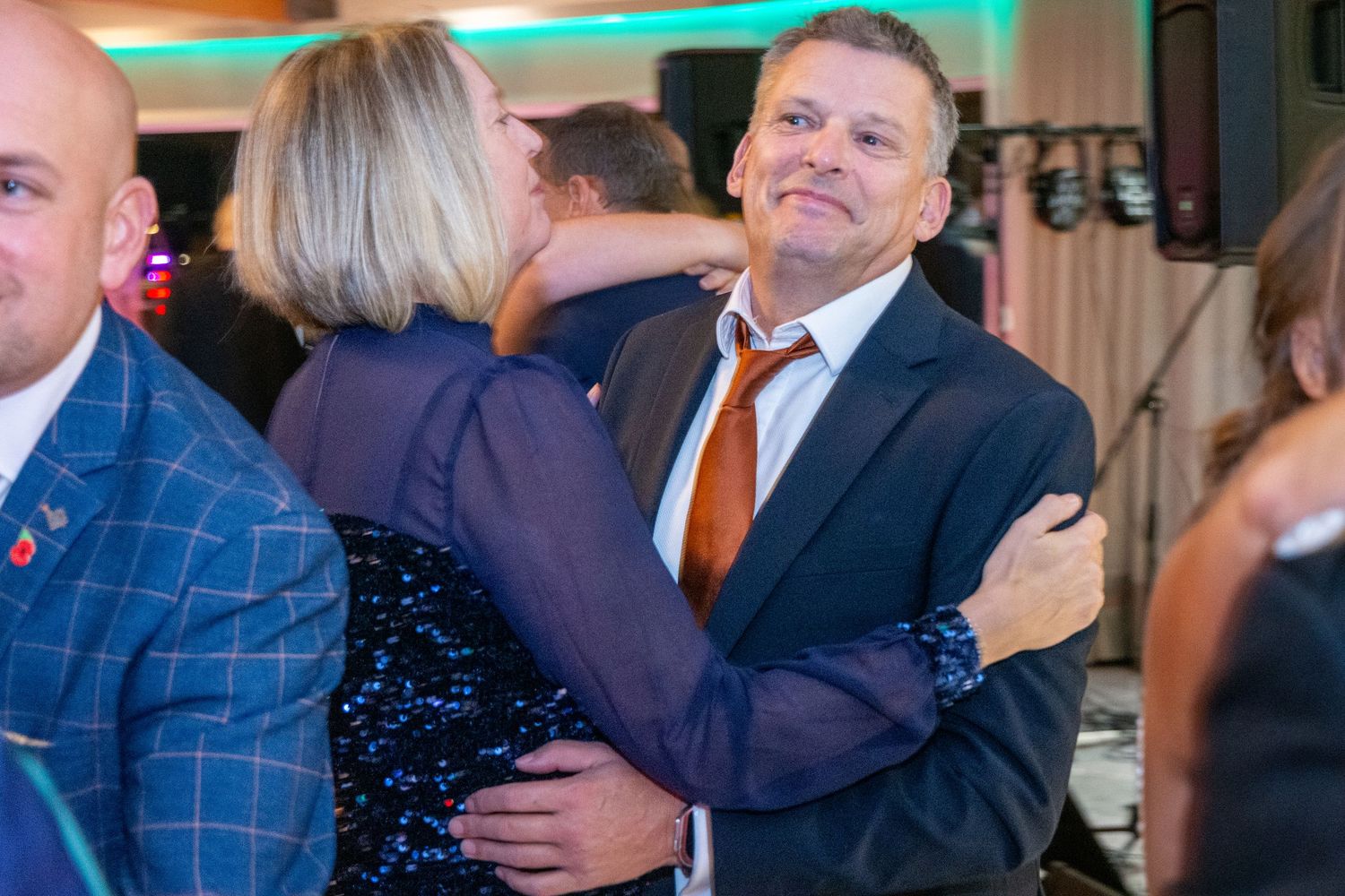 Man and woman sharing a warm embrace on a dance floor at a party.
