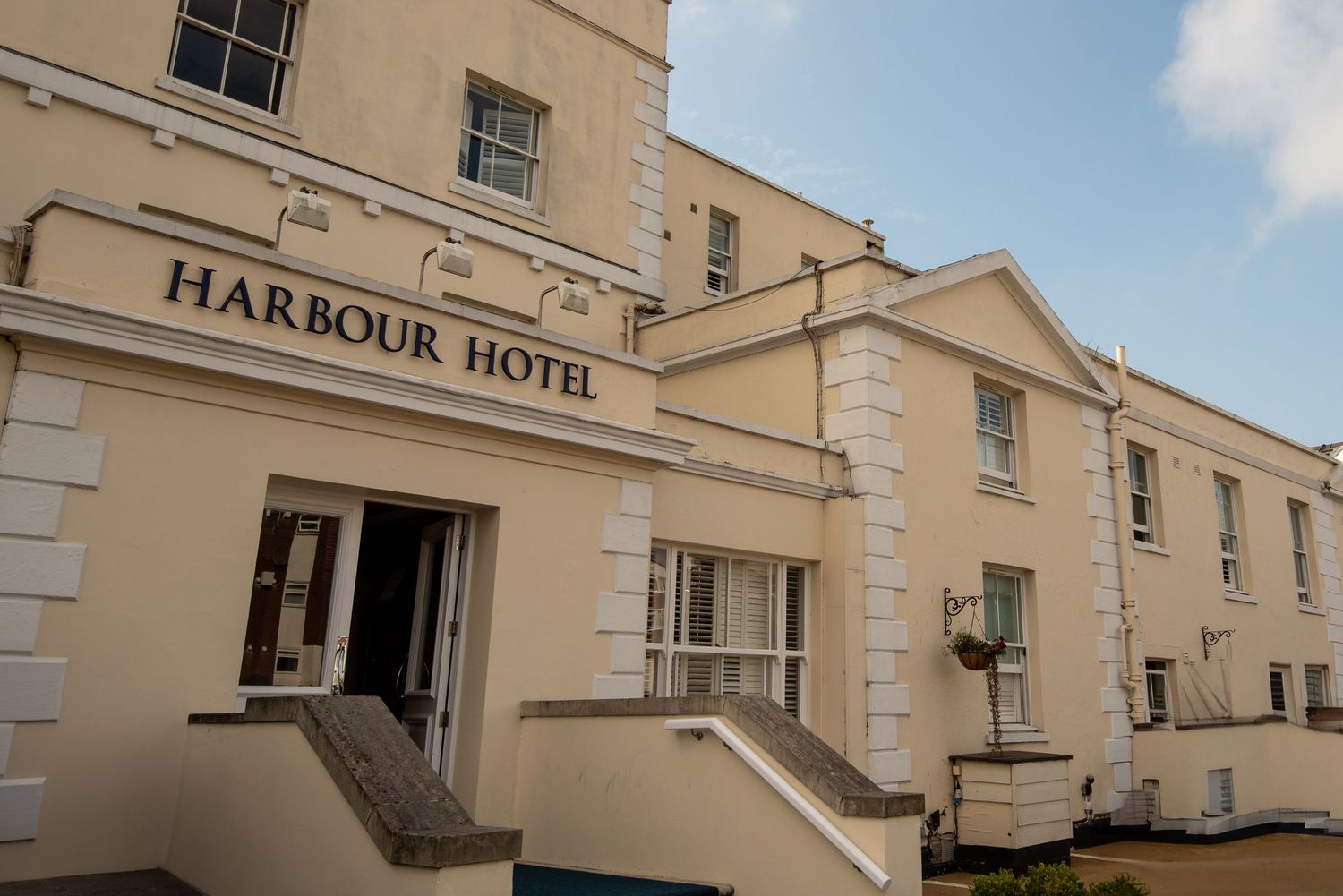Exterior view of the cream-colored Harbour Hotel building with classic architecture and columns in daylight.