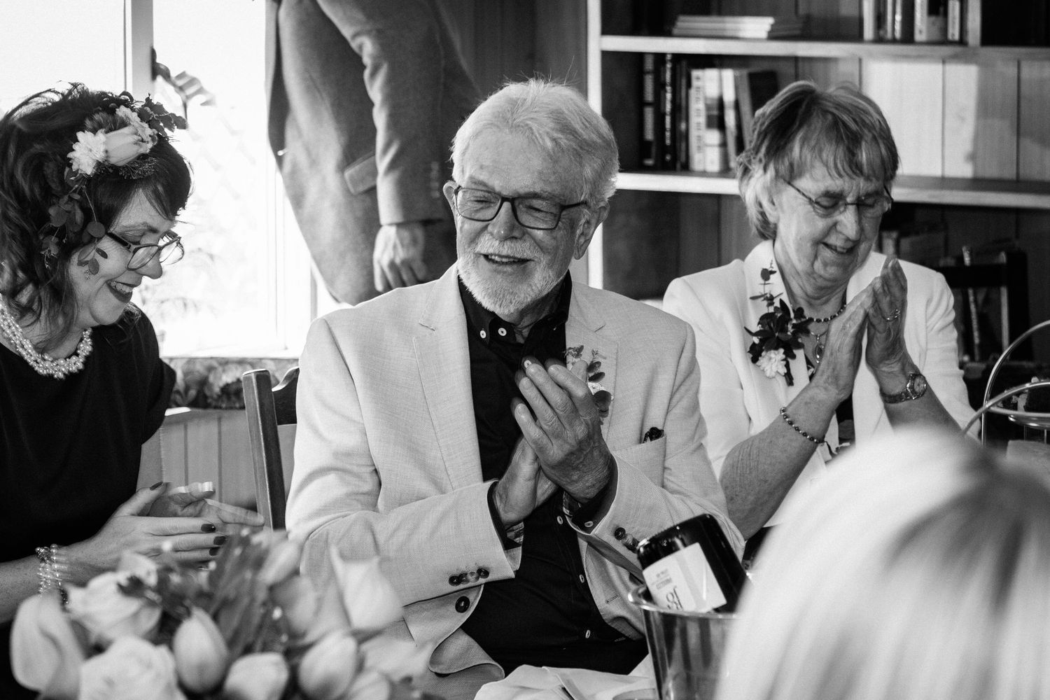 Black and white candid photo of guests laughing and enjoying themselves at a formal event.