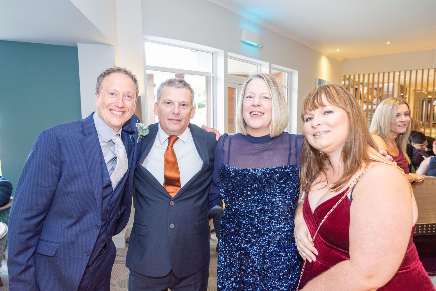 Four smartly dressed adults smiling together at a formal evening event.