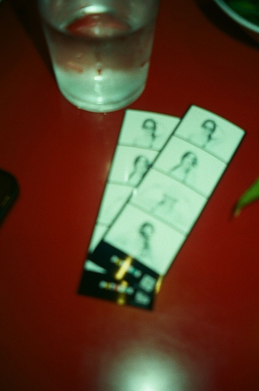 A B&W photo booth strip lays flat on a red table.
