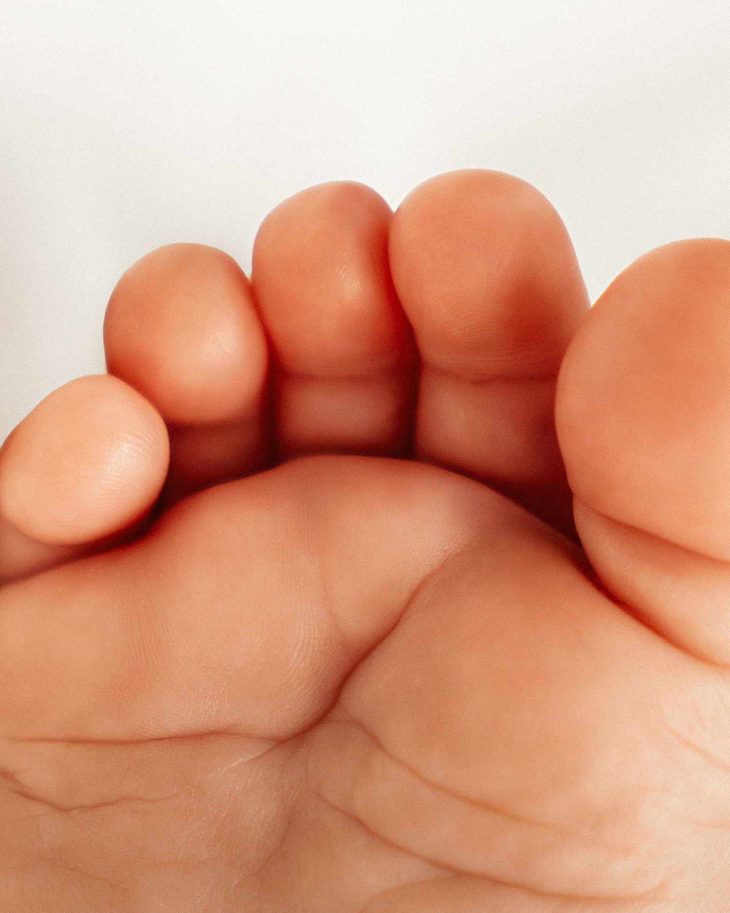 Close-up of a baby's tiny toes and foot sole against a white background.