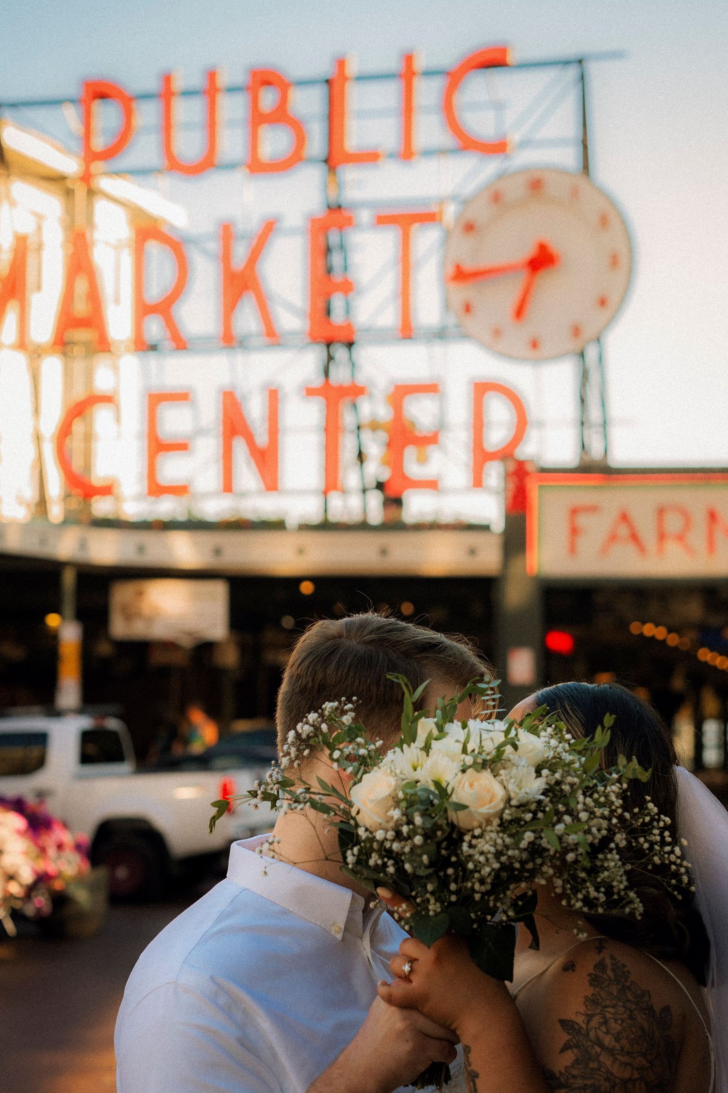 Couple kissing in front of the iconic Pike Place Public Market Center neon sign in Seattle, WA.