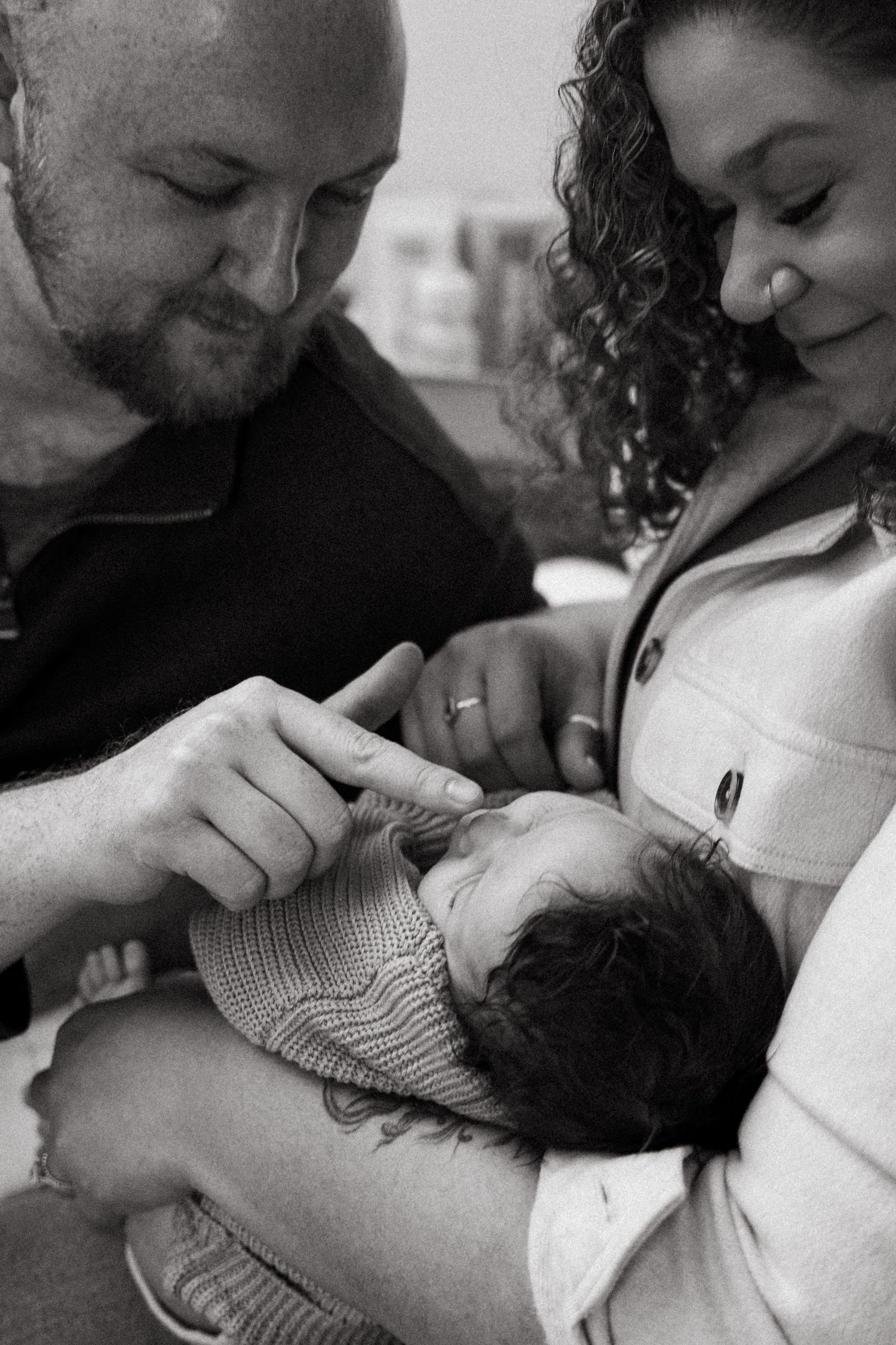Black and white photo of parents lovingly gazing at their newborn baby, a tender family moment captured.
