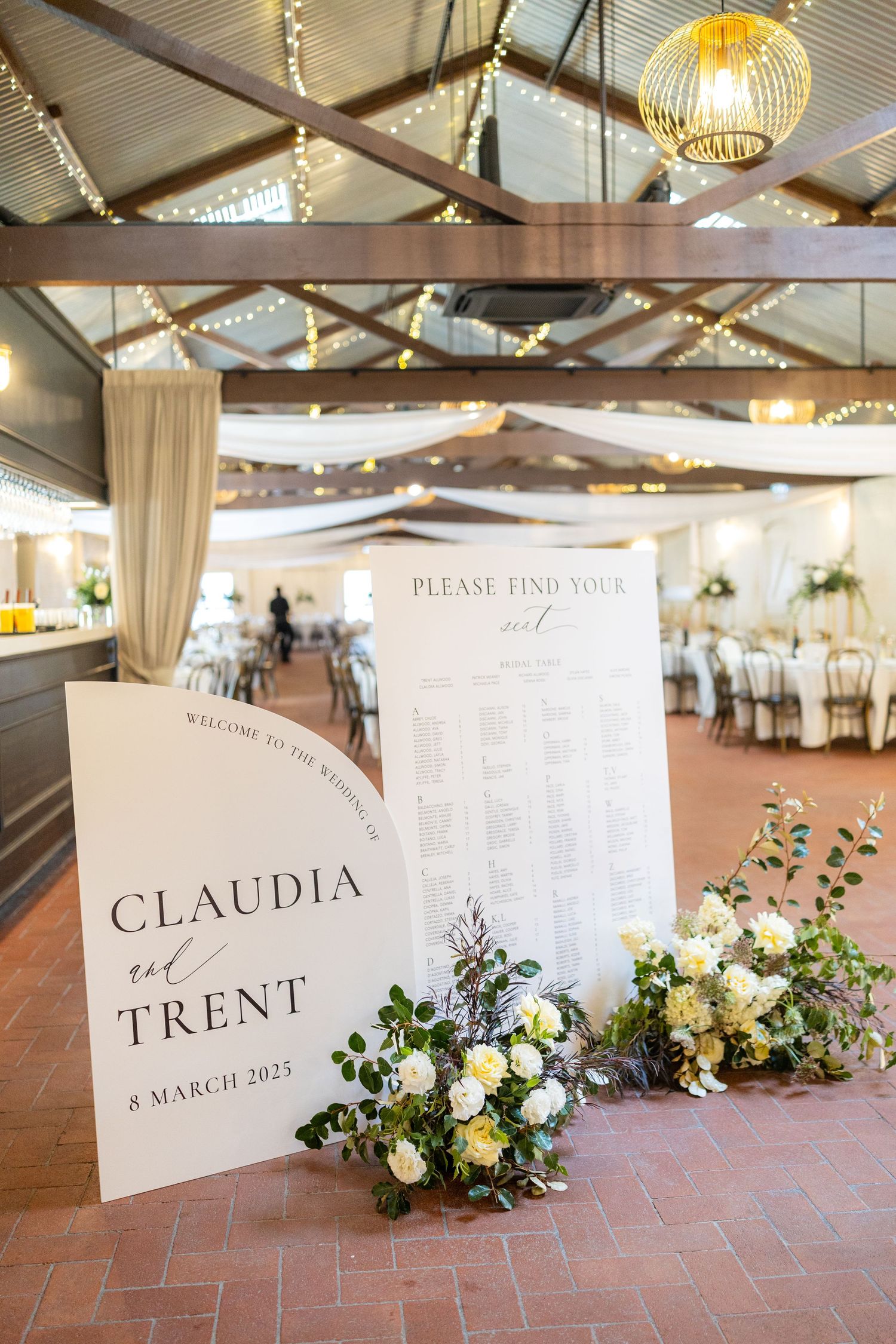Wedding welcome sign for Claudia and Trent dated 8 March 2025 with seating chart and floral arrangements.