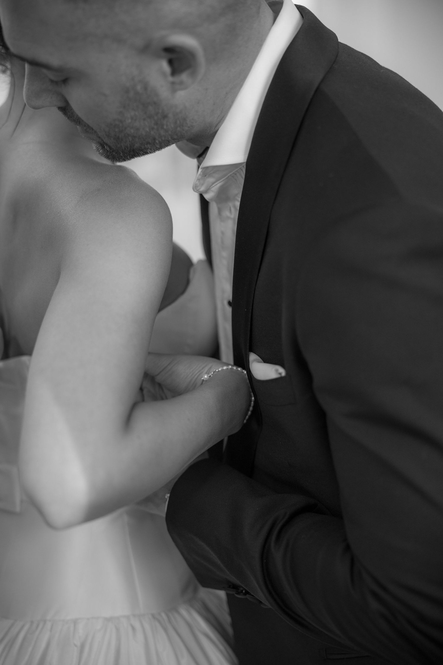 Black and white romantic close-up of bride and groom sharing a kiss on their wedding day.