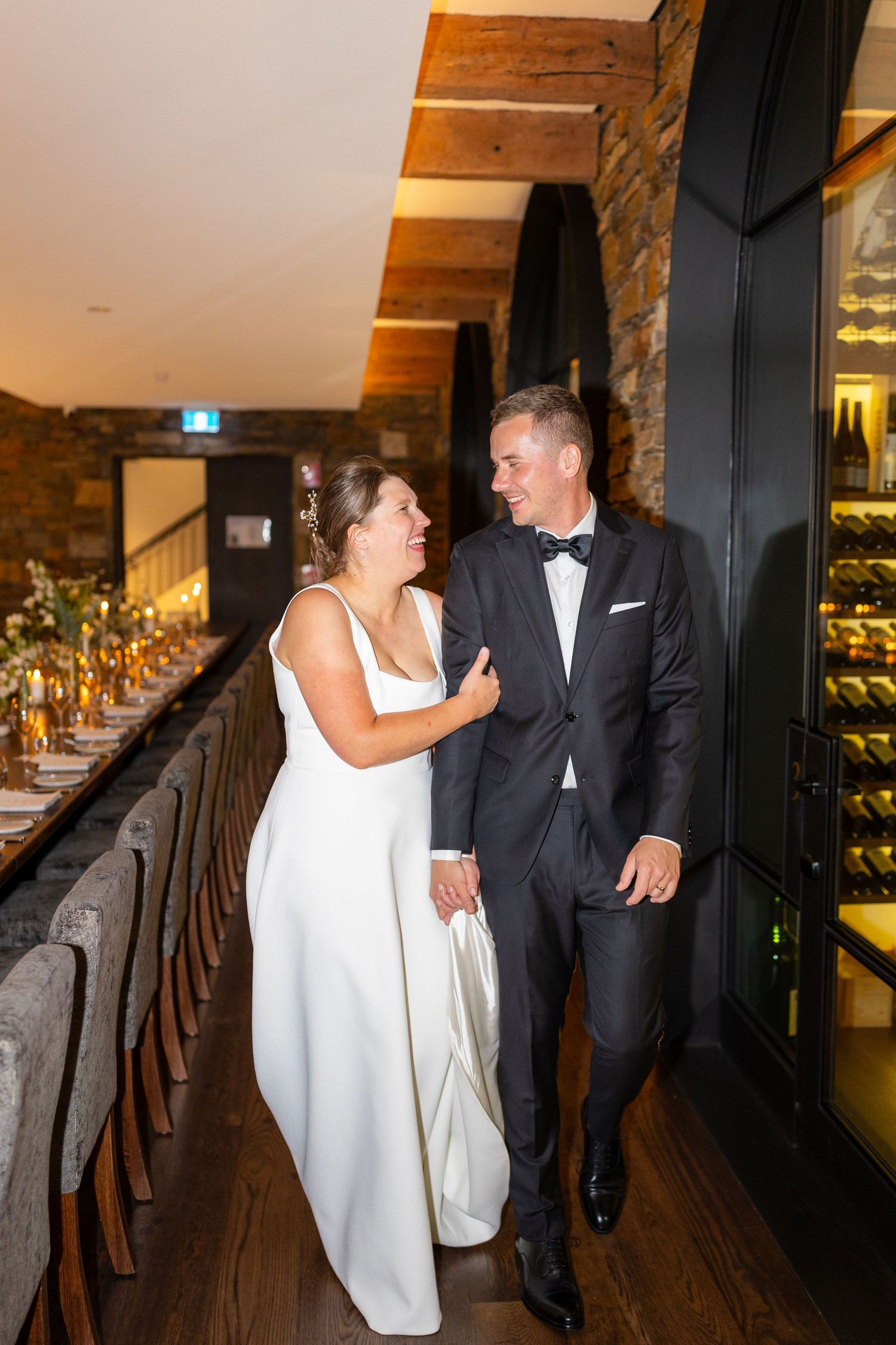 Bride and groom walking hand in hand through an elegant rustic wedding reception venue.