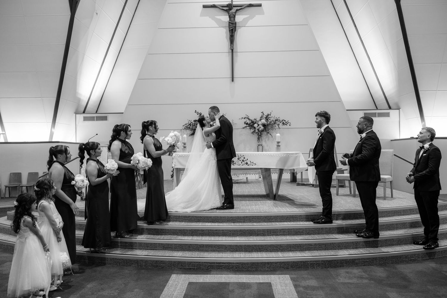 Black and white photo of a wedding ceremony at the altar of a Catholic church.