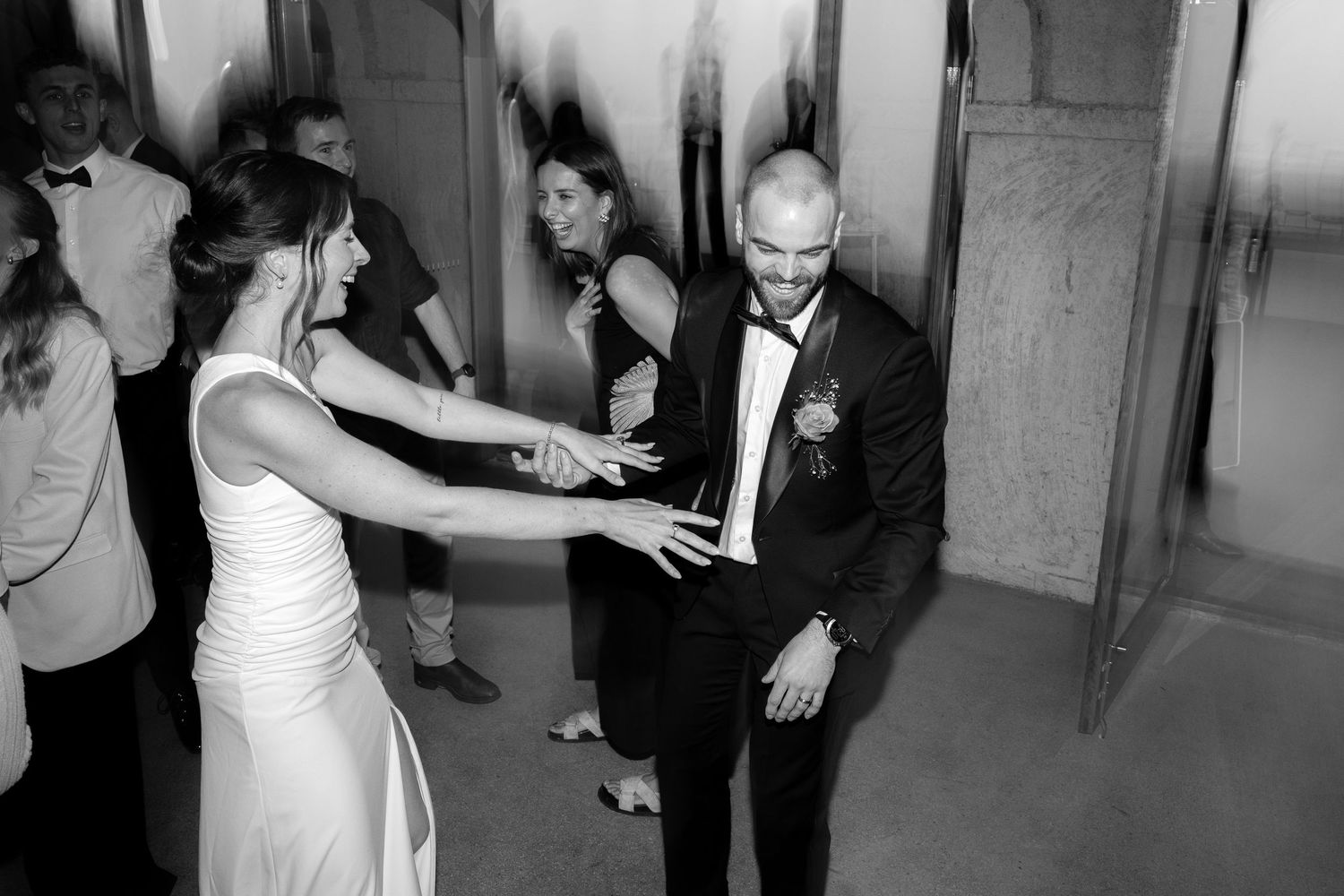 Bride and groom share a joyful dance moment at their wedding reception in black and white photography.