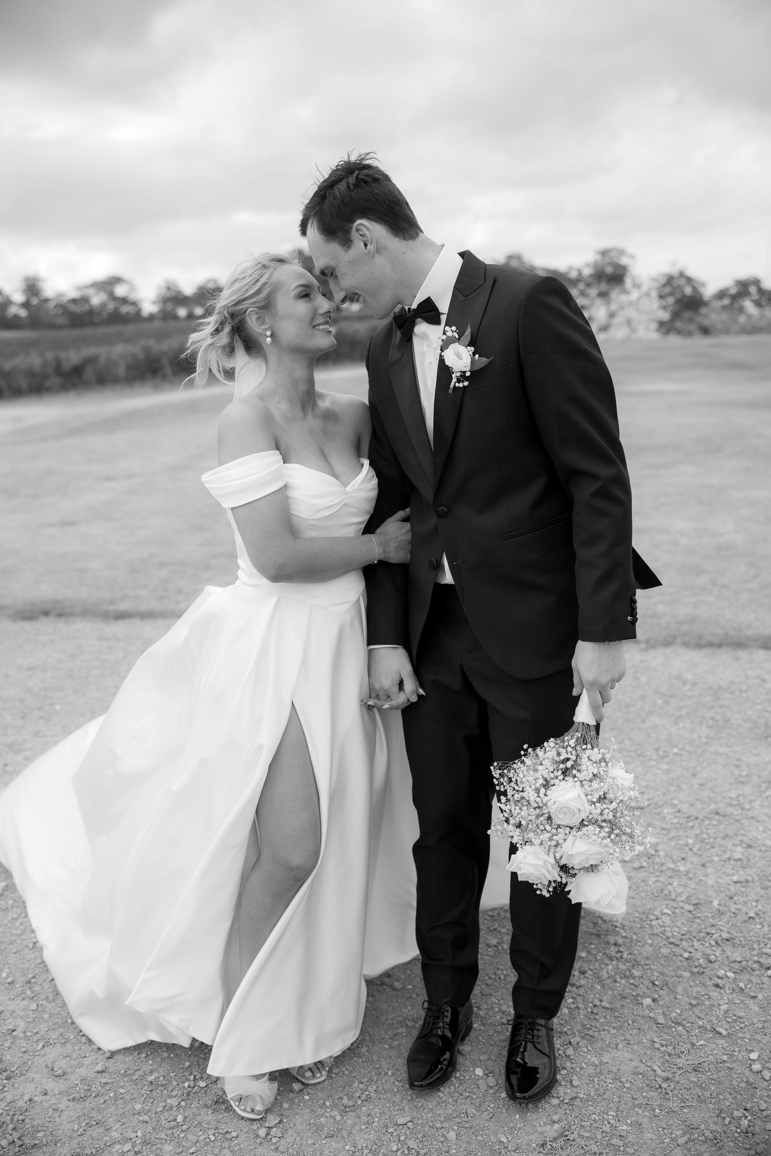 Black and white romantic photo of bride and groom nearly kissing at vineyard wedding.