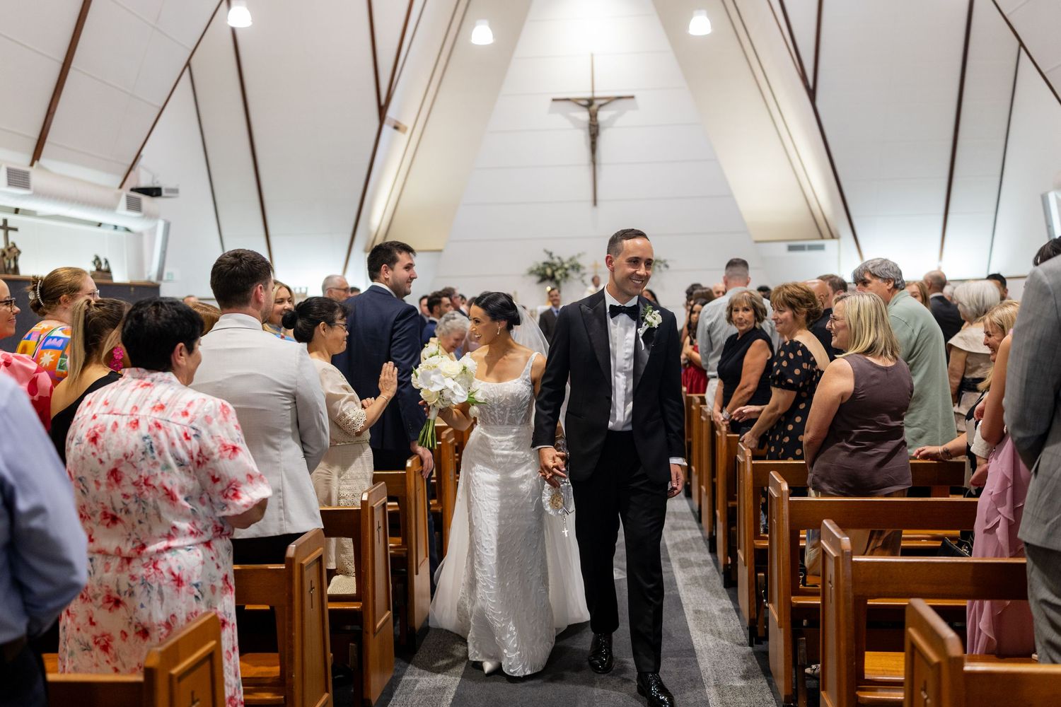 Newlyweds walking hand in hand down the church aisle after their wedding ceremony.