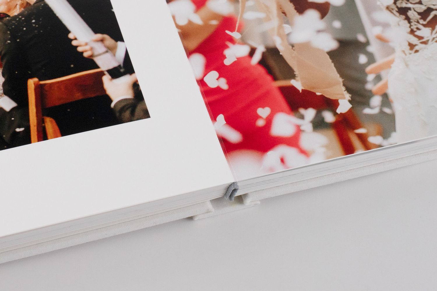 Close-up of open wedding album pages showing ceremony and confetti celebration photos with layflat binding.