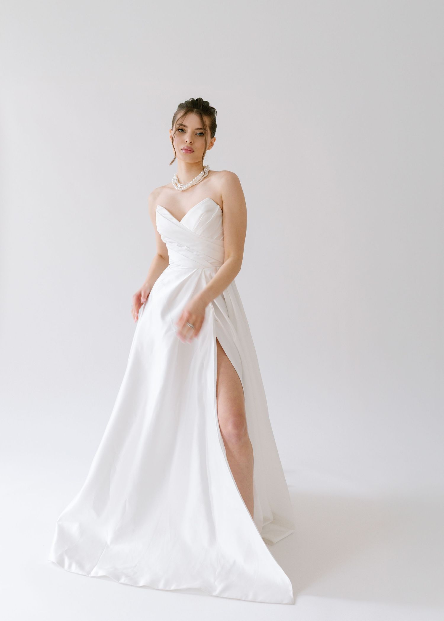 Elegant strapless white A-line wedding gown with sweetheart neckline, lace bodice, and thigh-high slit on a model.