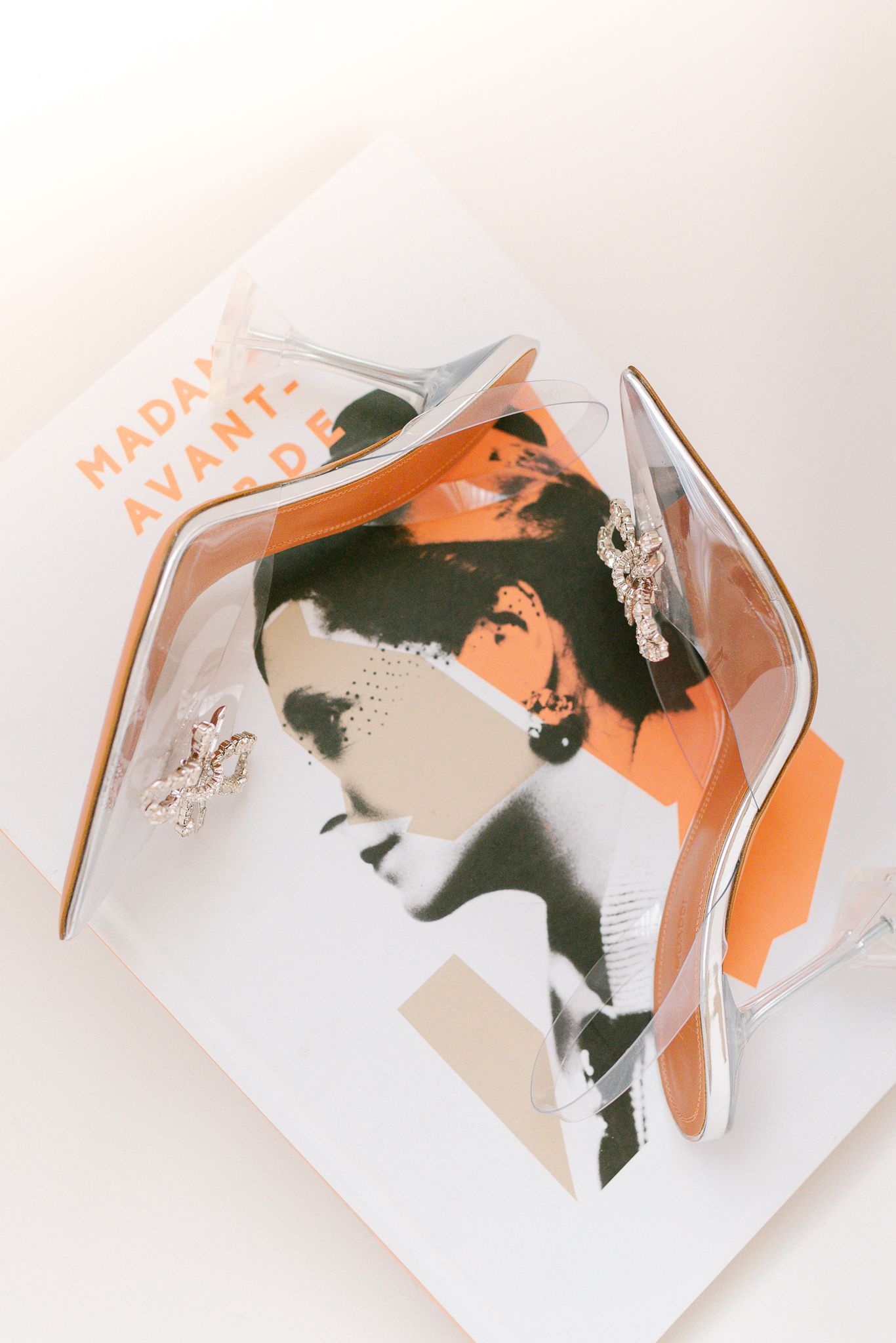 Clear perspex bridal heels with crystal embellishments resting on a Madame Avant-Garde magazine cover.