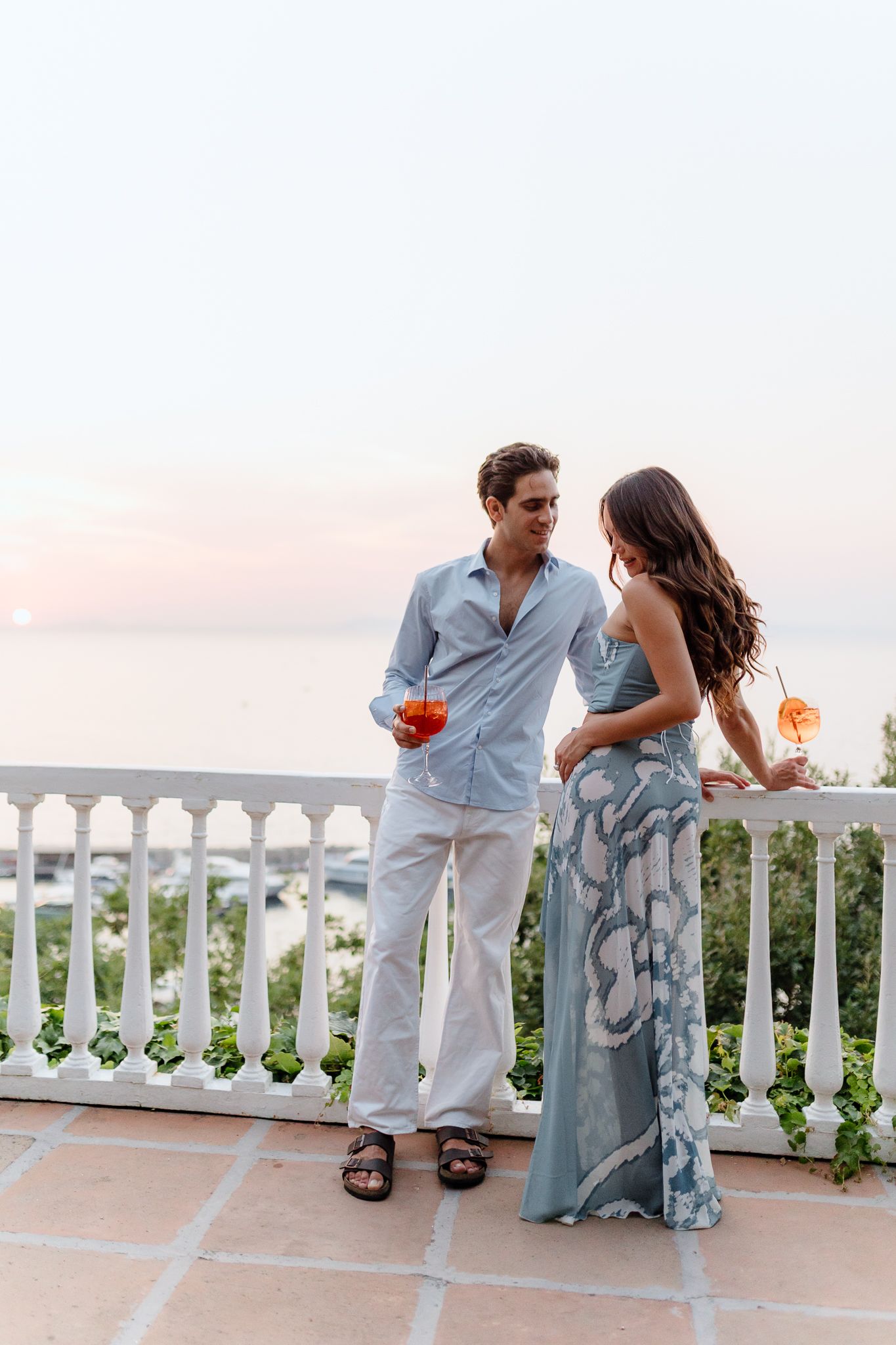 Couple enjoying Aperol Spritz cocktails on a white balcony at sunset by the Sean in Villa Silvana,Sorrento,Italy.