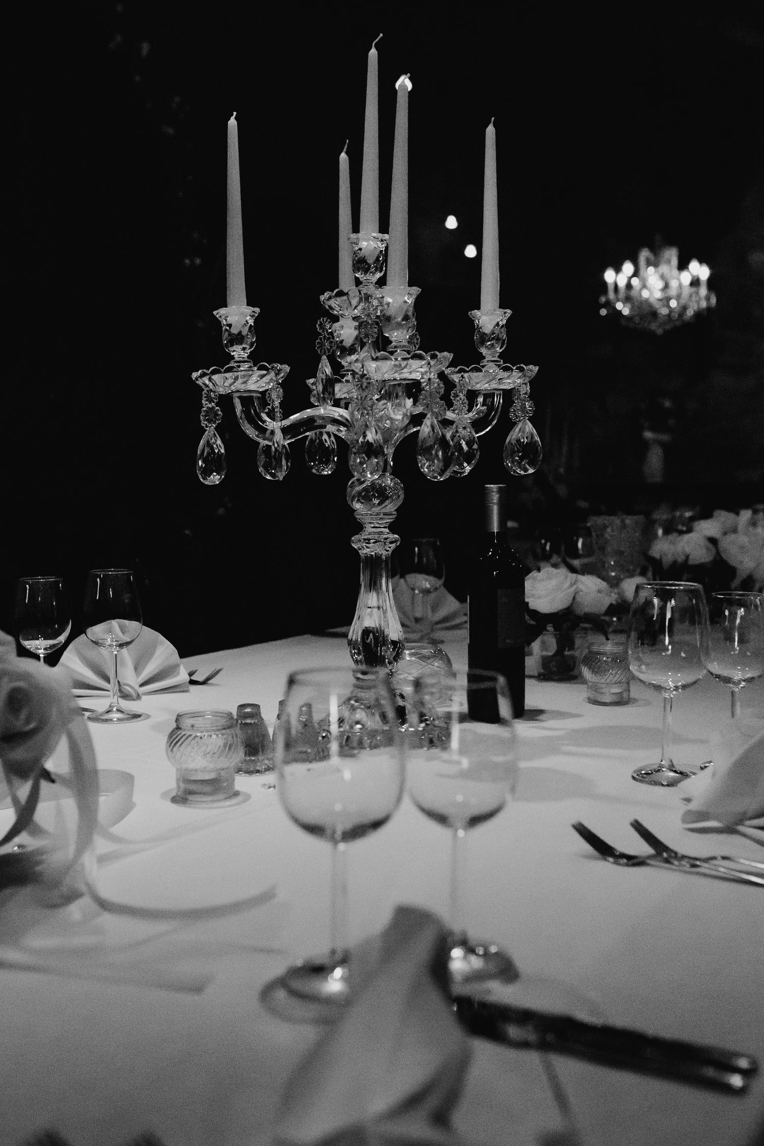 Elegant crystal candelabra centerpiece on white wedding reception table in black and white photo.