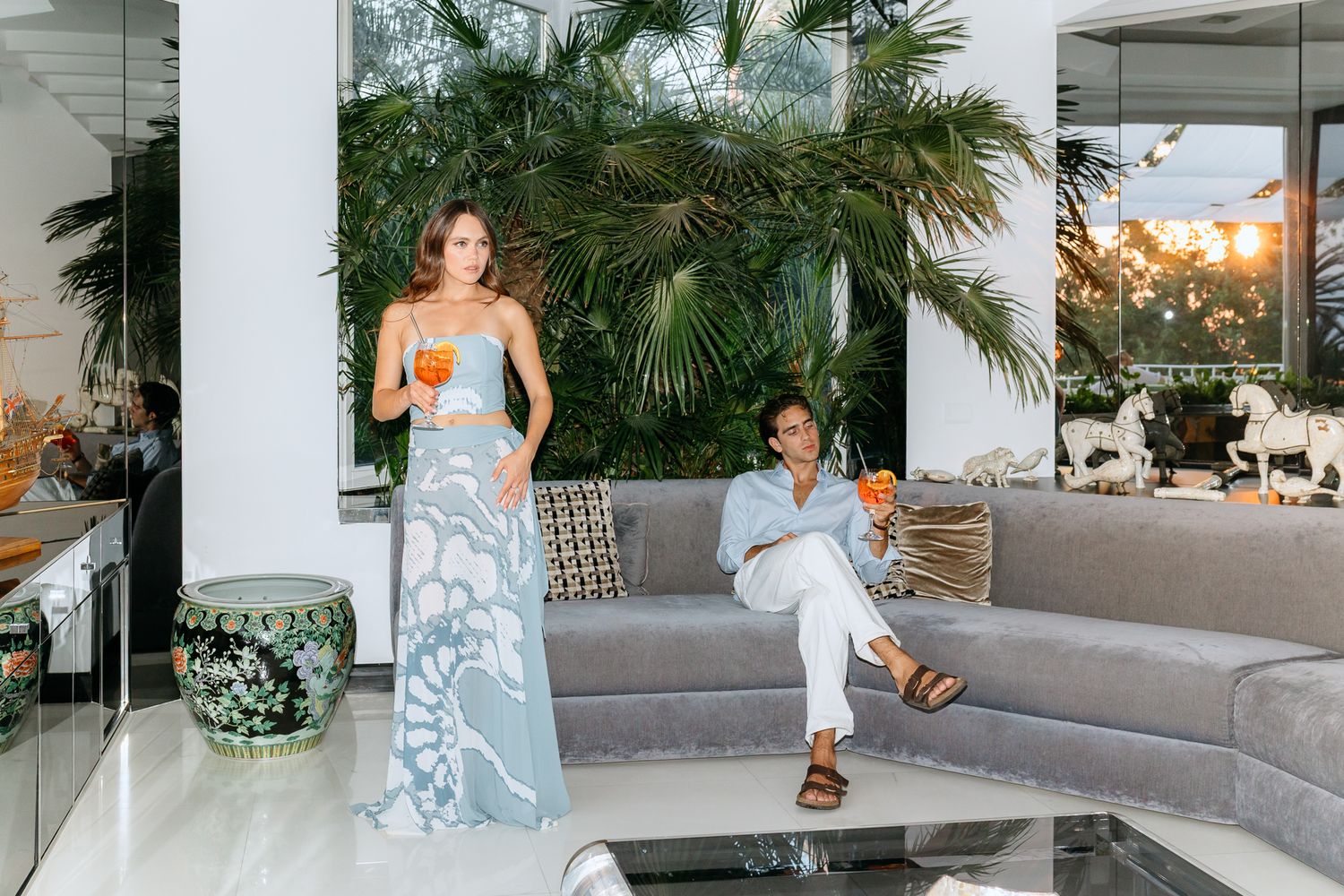 Fashionable couple relaxing in a luxurious modern lounge surrounded by tropical plants and cocktails in Villa Silvana.