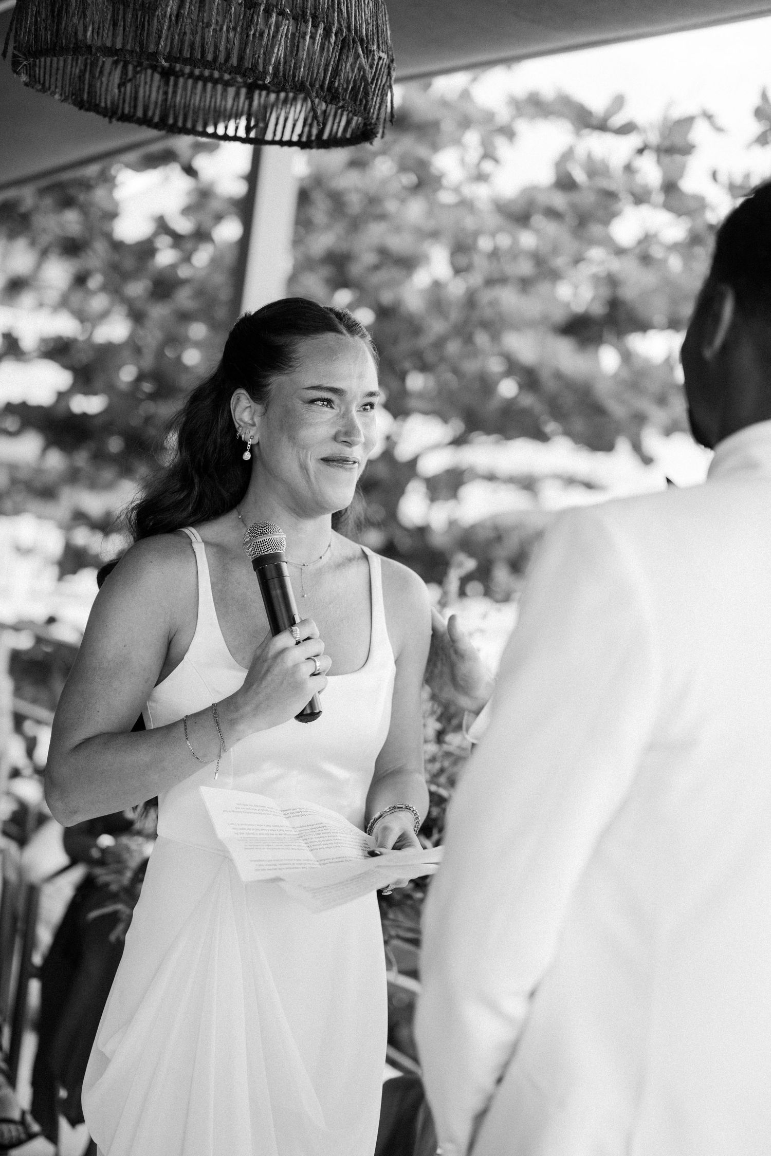 Bride reads vows into microphone while facing groom during outdoor wedding ceremony. Barbados Destination Wedding Photographer