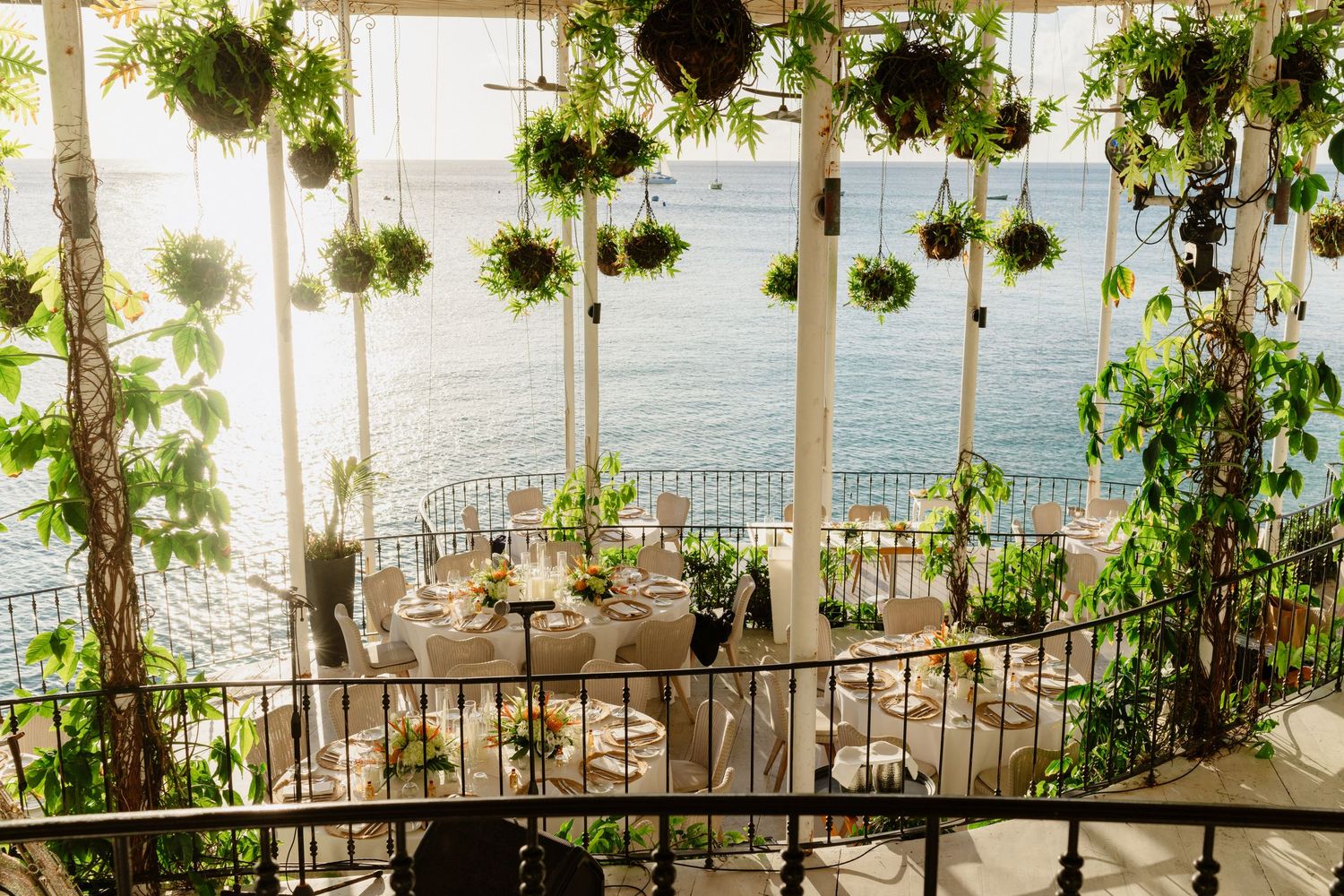Romantic oceanview wedding reception venue with hanging greenery and elegant table setting on terrace. QP Bistro, Barbados