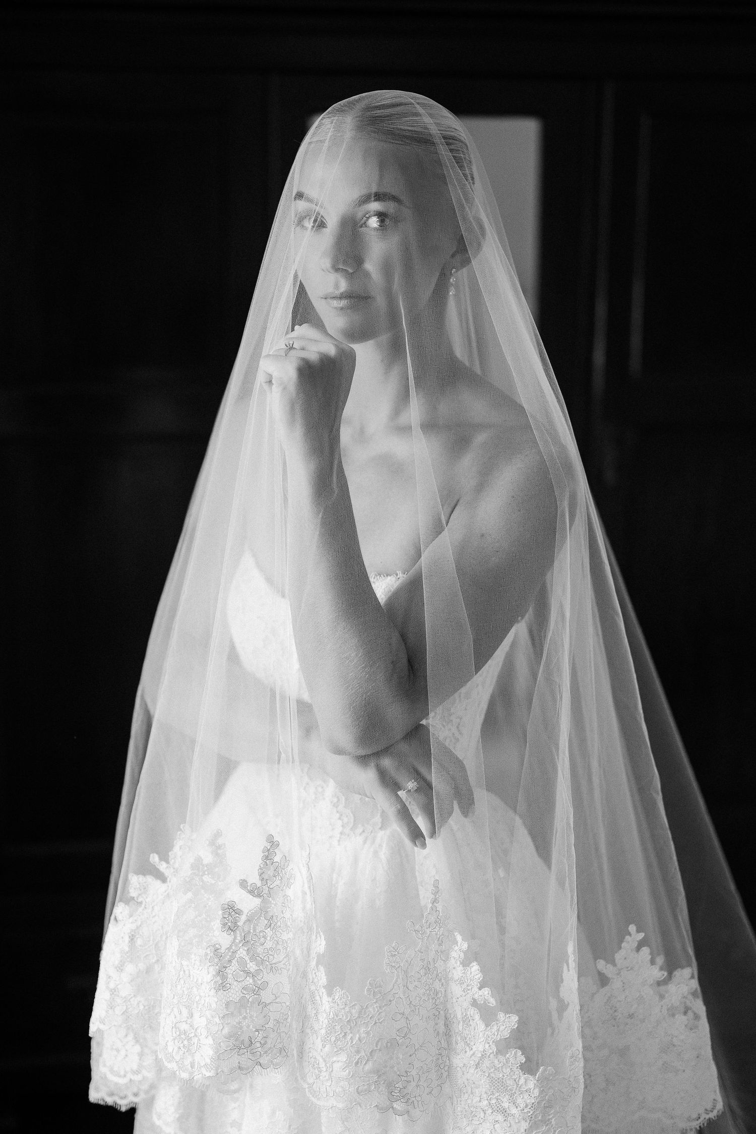 Stunning bride in lace wedding dress draped in sheer veil captured in black and white portrait. Barbados Destination Wedding Photographer