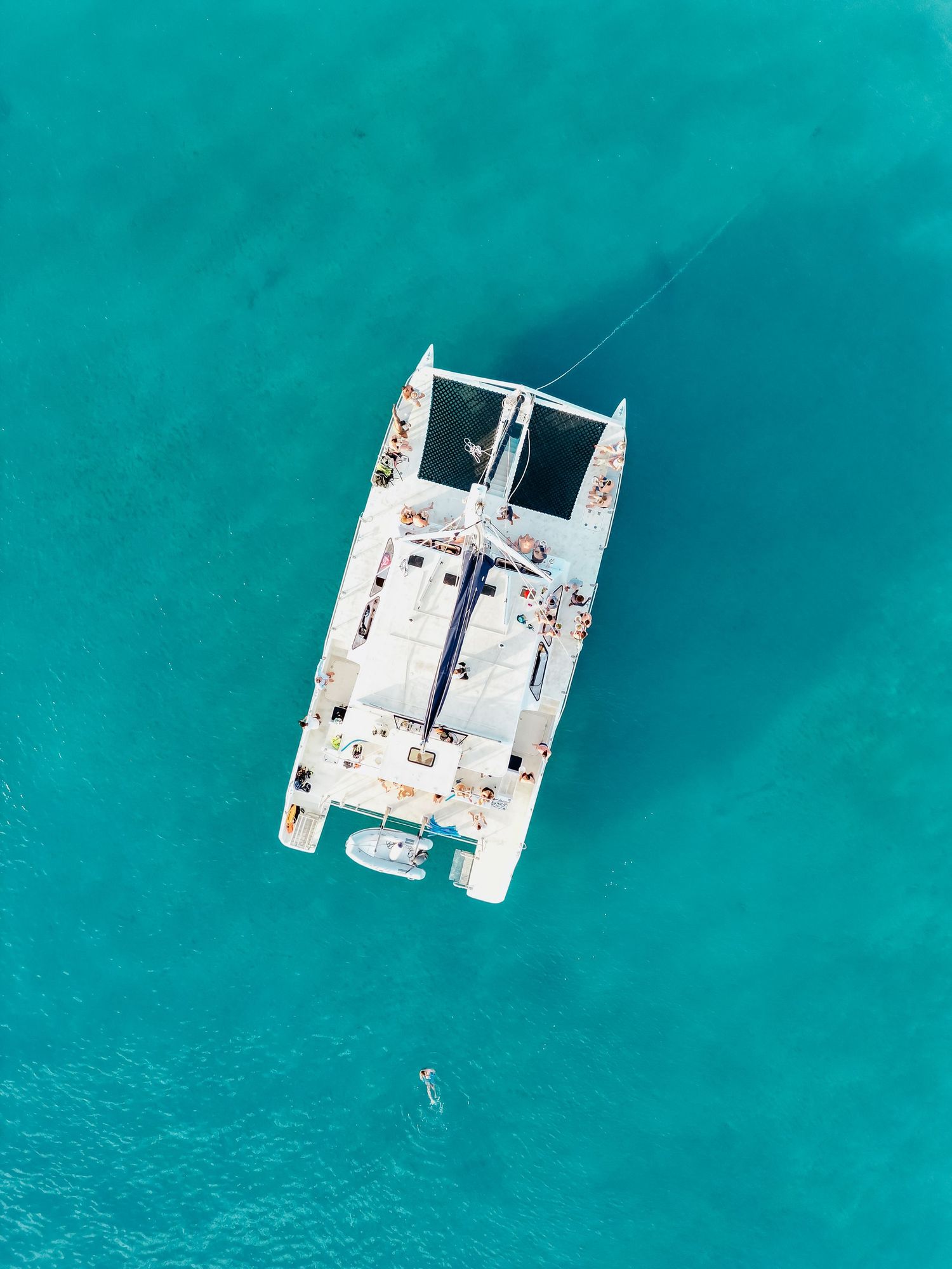 Aerial view of a white catamaran anchored in vibrant turquoise Caribbean waters on a sunny day. Barbados photographer