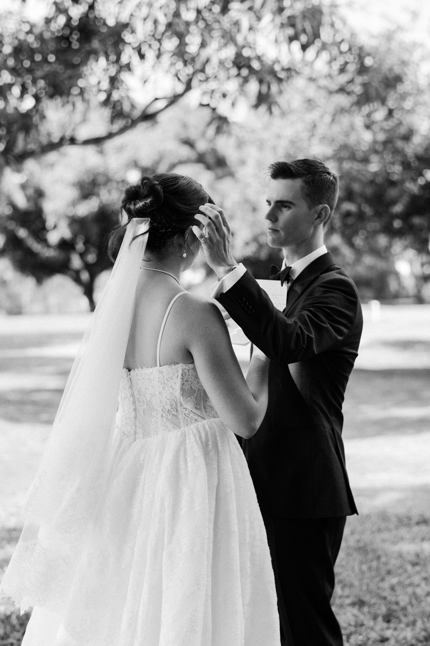 Black and white photo of groom gently touching bride's veil during an emotional first look outdoors. Barbados Destination Wedding Photograph