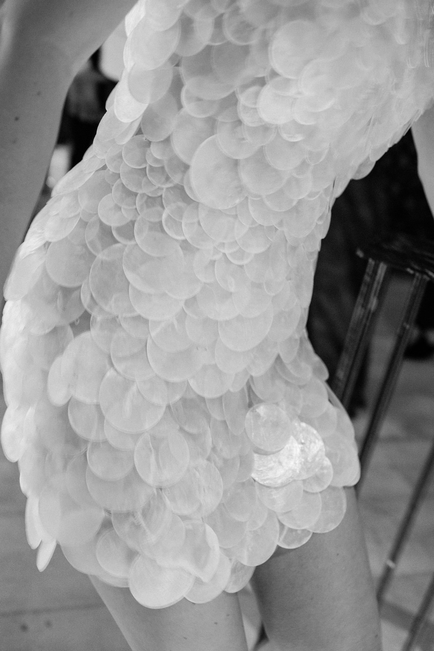 Close-up black and white detail of bride wearing unique circular paillette sequin wedding dress sleeve.