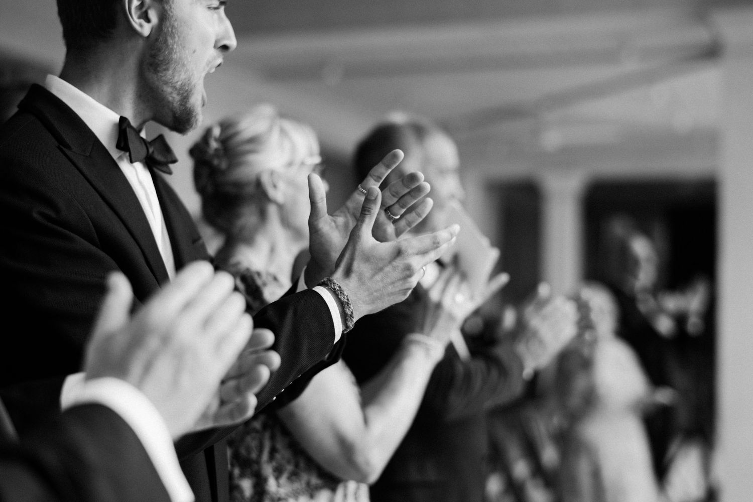 Wedding guests in formal attire applaud during black and white reception celebration moment. Barbados photographer