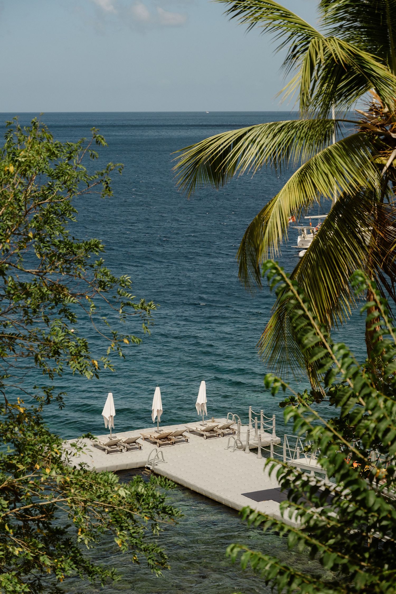 Serene overwater dock with white lounge chairs and umbrellas overlooking calm turquoise Caribbean waters. St Lucia Wedding photographer