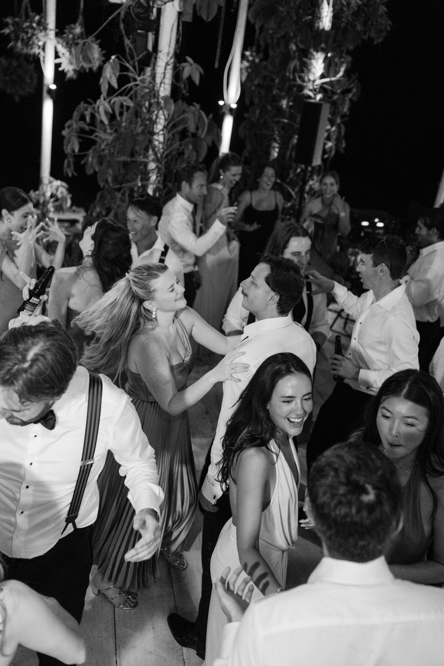 Wedding guests celebrate joyfully on the dance floor during lively outdoor reception at night. Barbados Destination Wedding Photographer