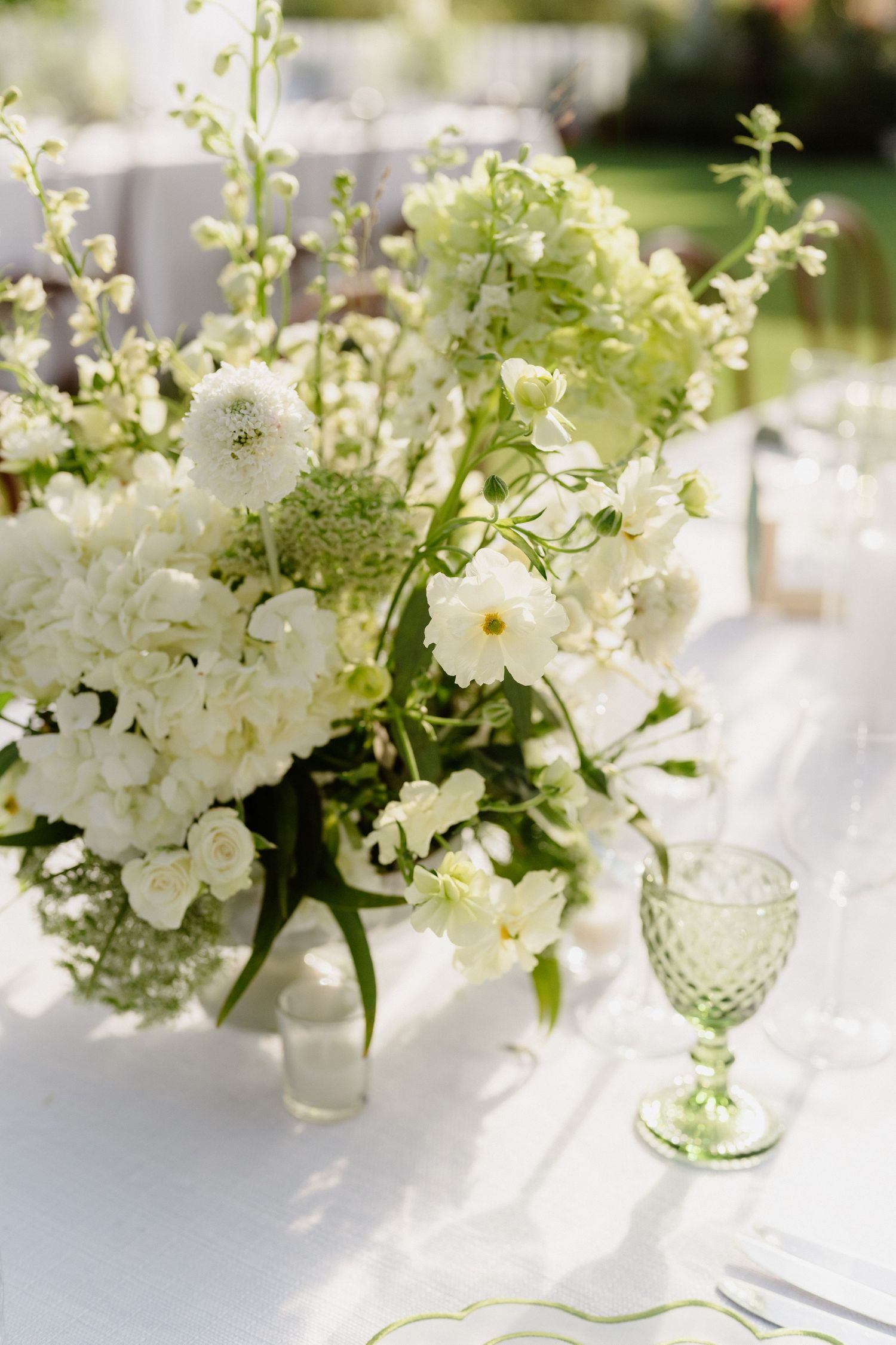 Elegant white and green floral centerpiece with textured goblet on white linen reception table. Barbados Destination Wedding Photographer