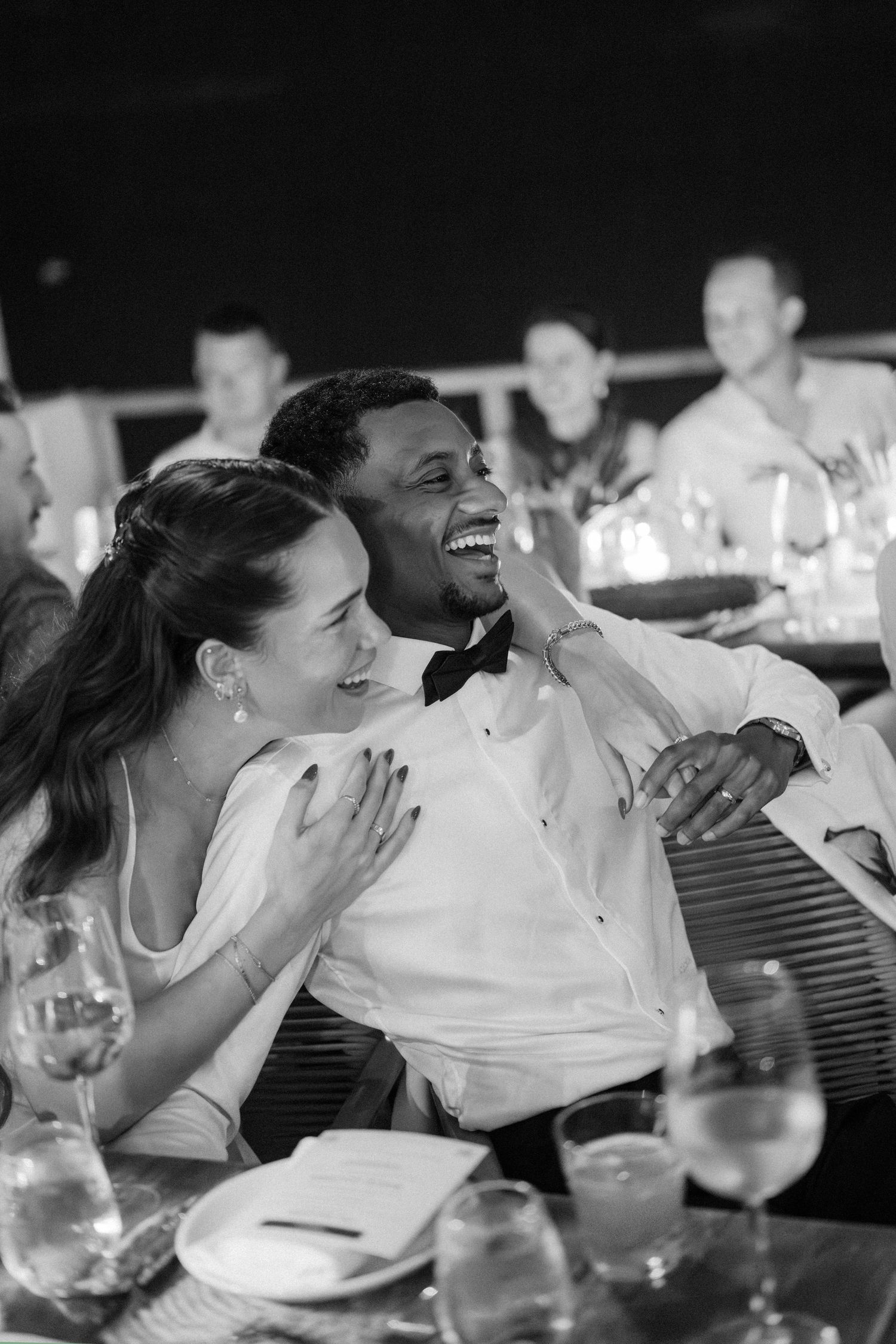 Black and white photo of laughing bride and groom sharing joyful moment at wedding reception. Barbados photographer