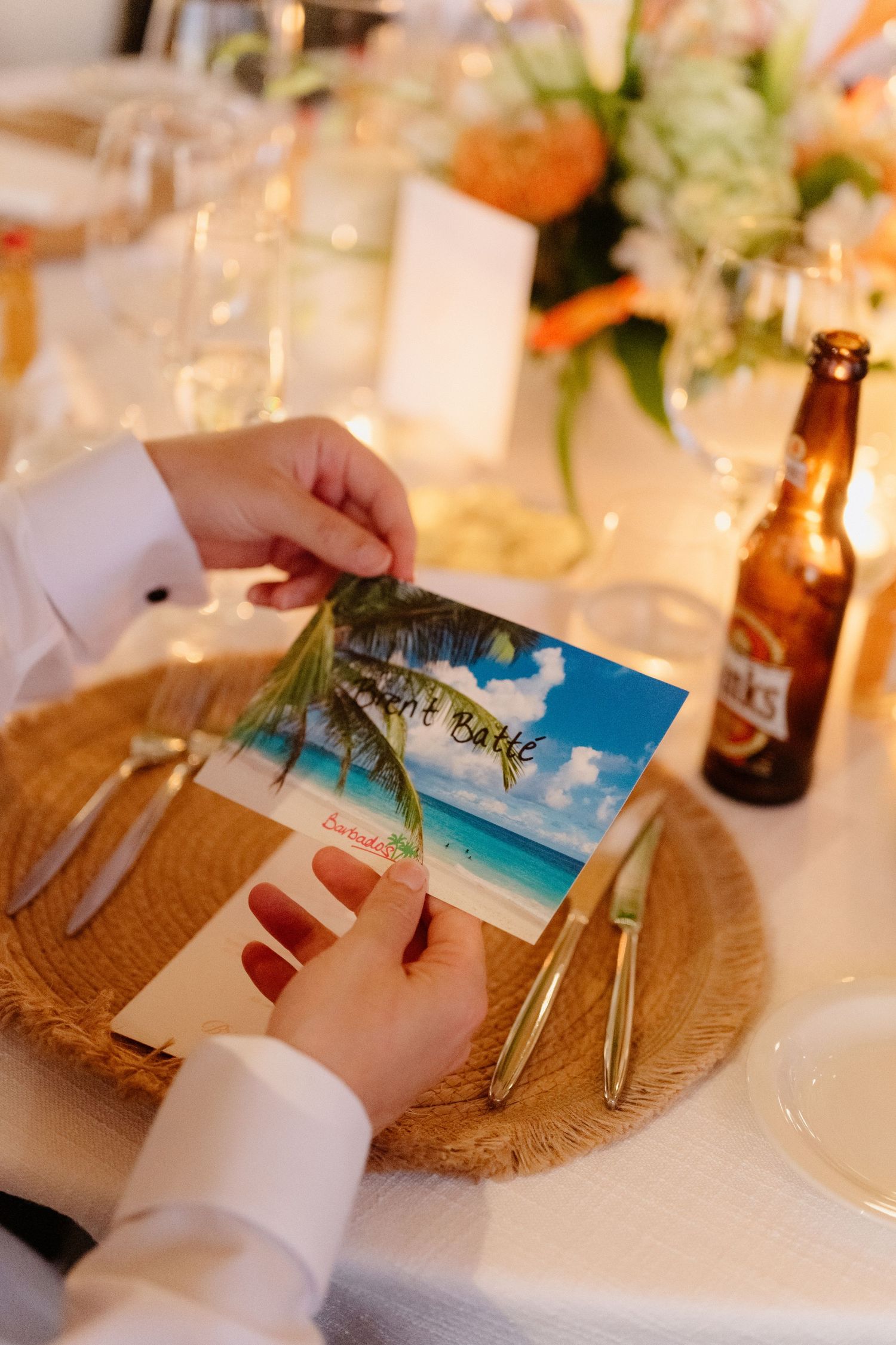 Wedding guest holds tropical beach-themed place card at elegantly decorated reception dinner. Barbados Destination Wedding Photographer