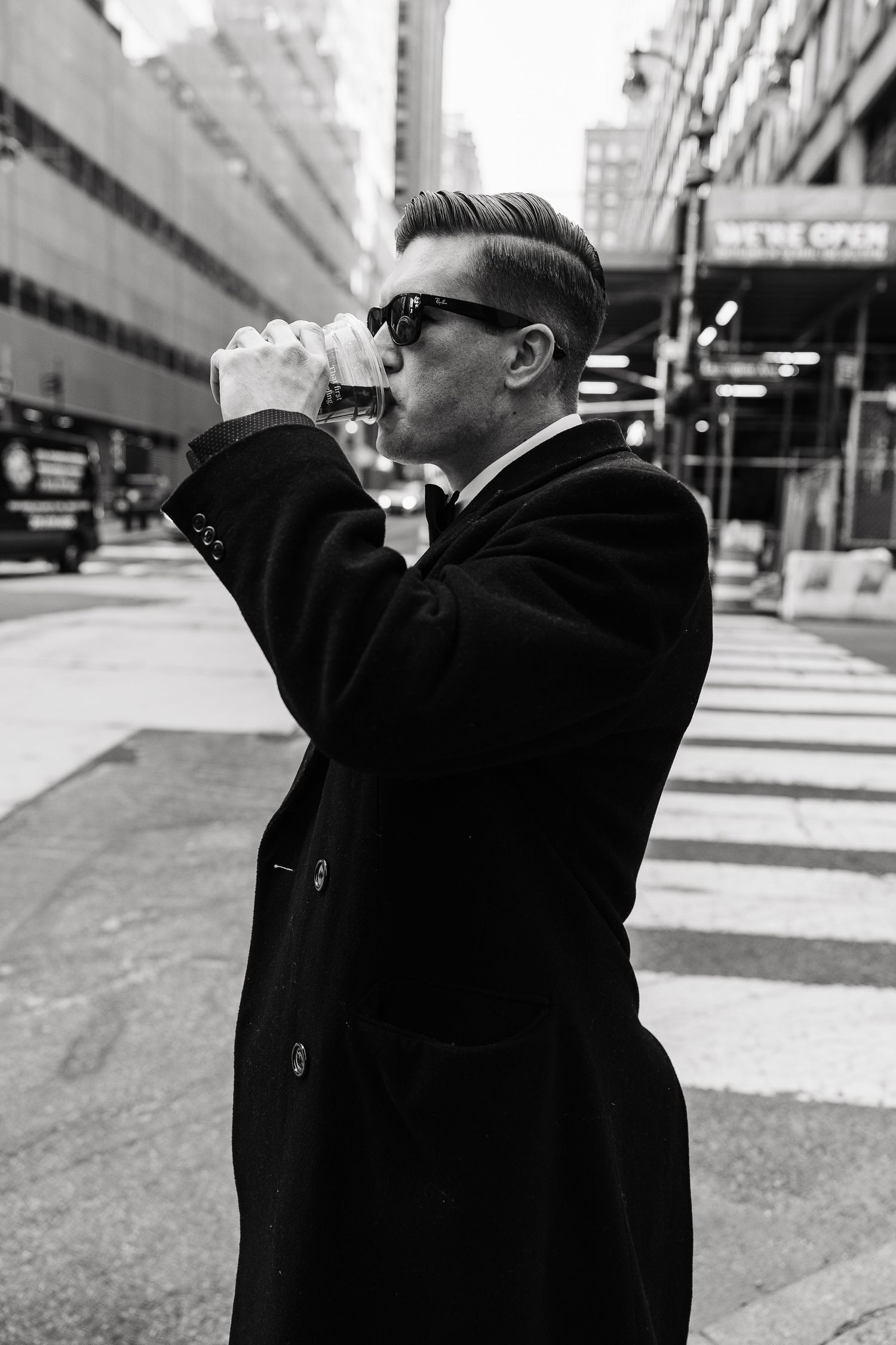 Stylish man in black coat and sunglasses drinking coffee on busy New York City street.  | Karina Thomson Photography Raleigh NC