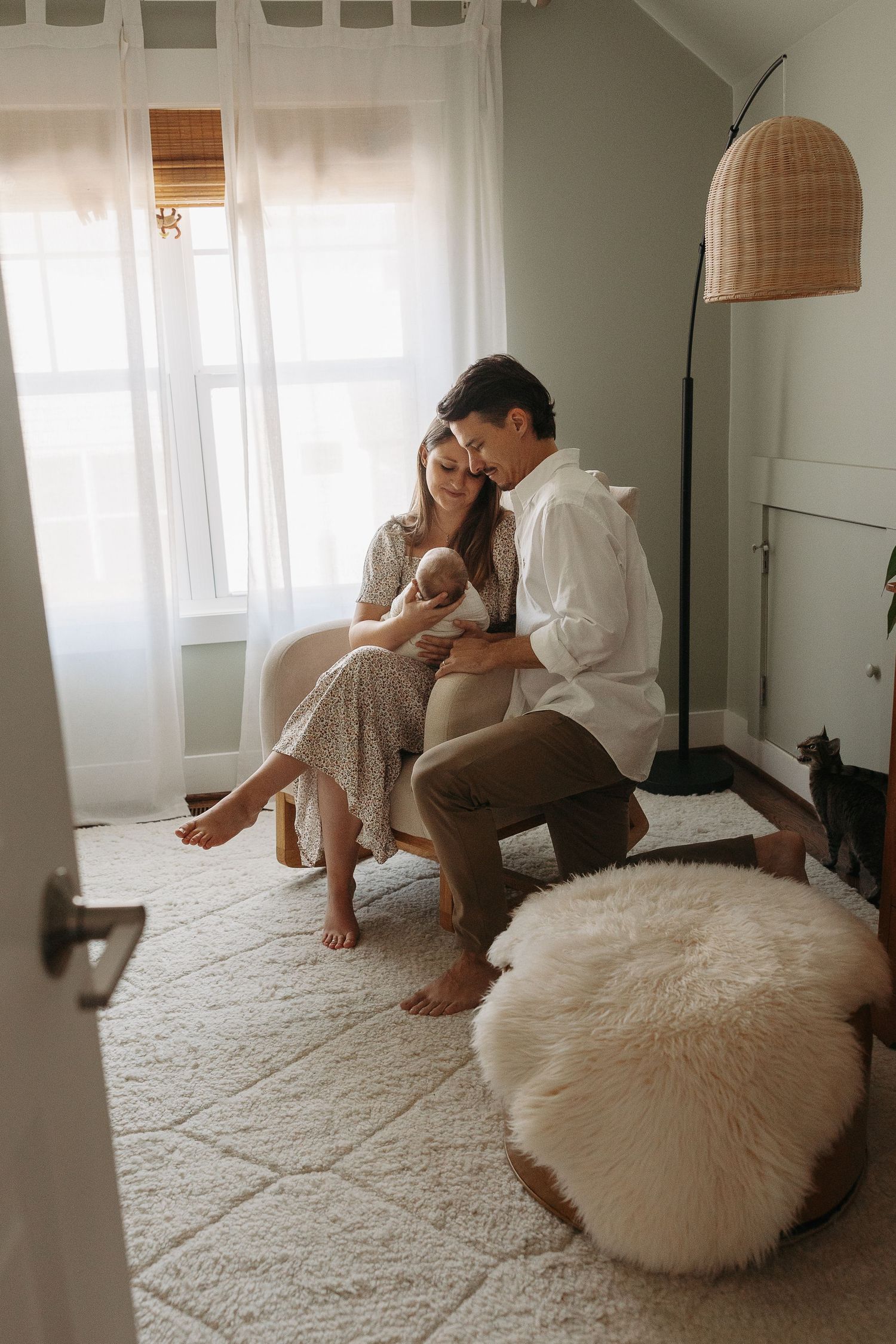 New parents sitting closely together in a cozy nursery, lovingly gazing at their newborn baby.  | Karina Thomson Photography Raleigh NC
