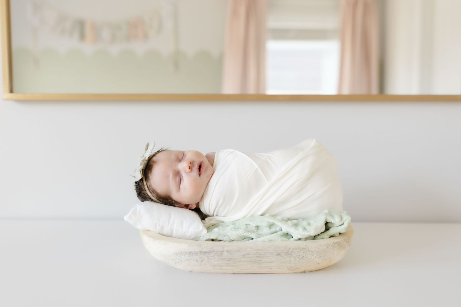 Peaceful newborn baby swaddled in white wrap sleeping in wicker bassinet in nursery.  | Karina Thomson Photography Raleigh NC