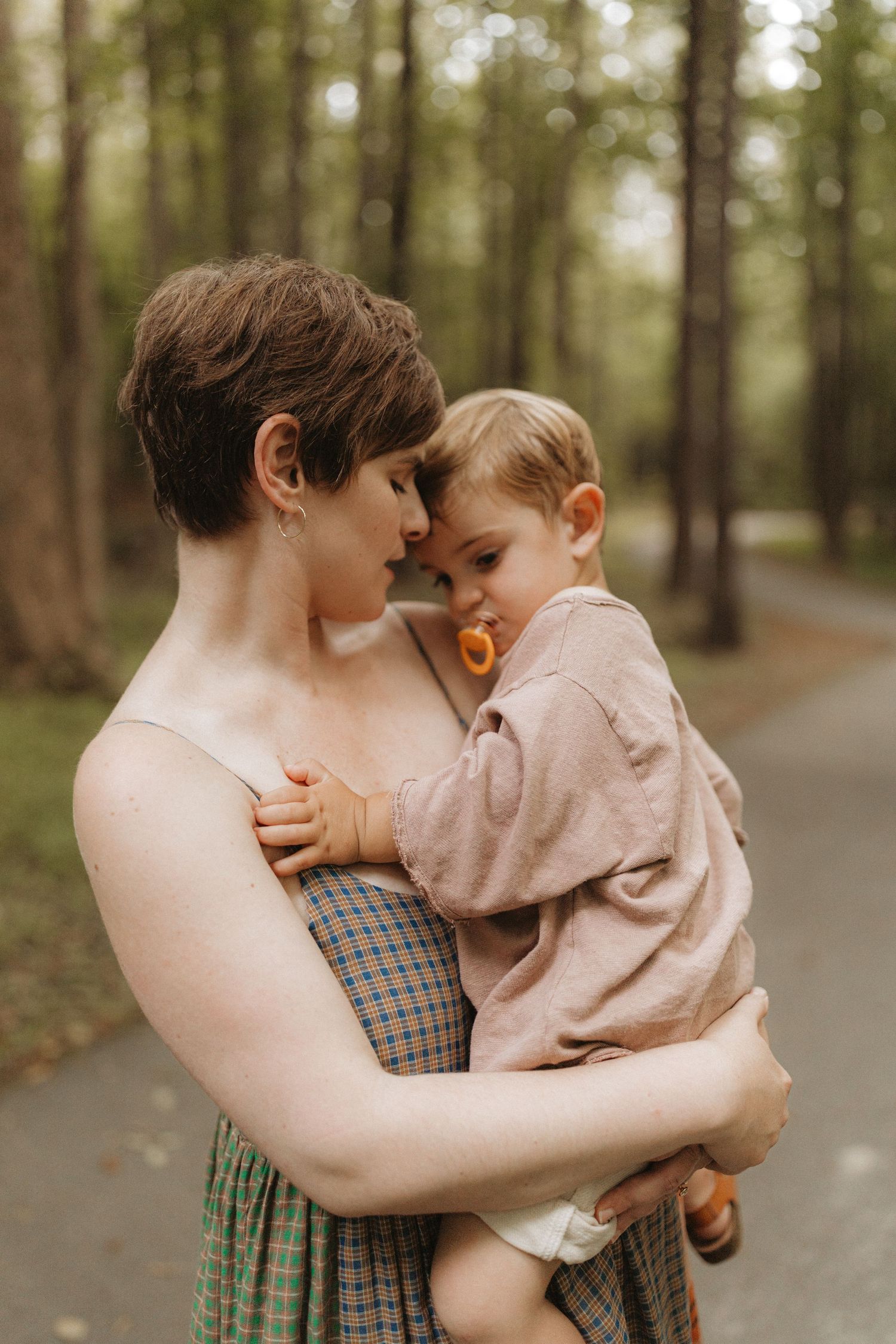 Mother holds toddler nose-to-nose in a tender moment on a forest path.  | Karina Thomson Photography Raleigh NC