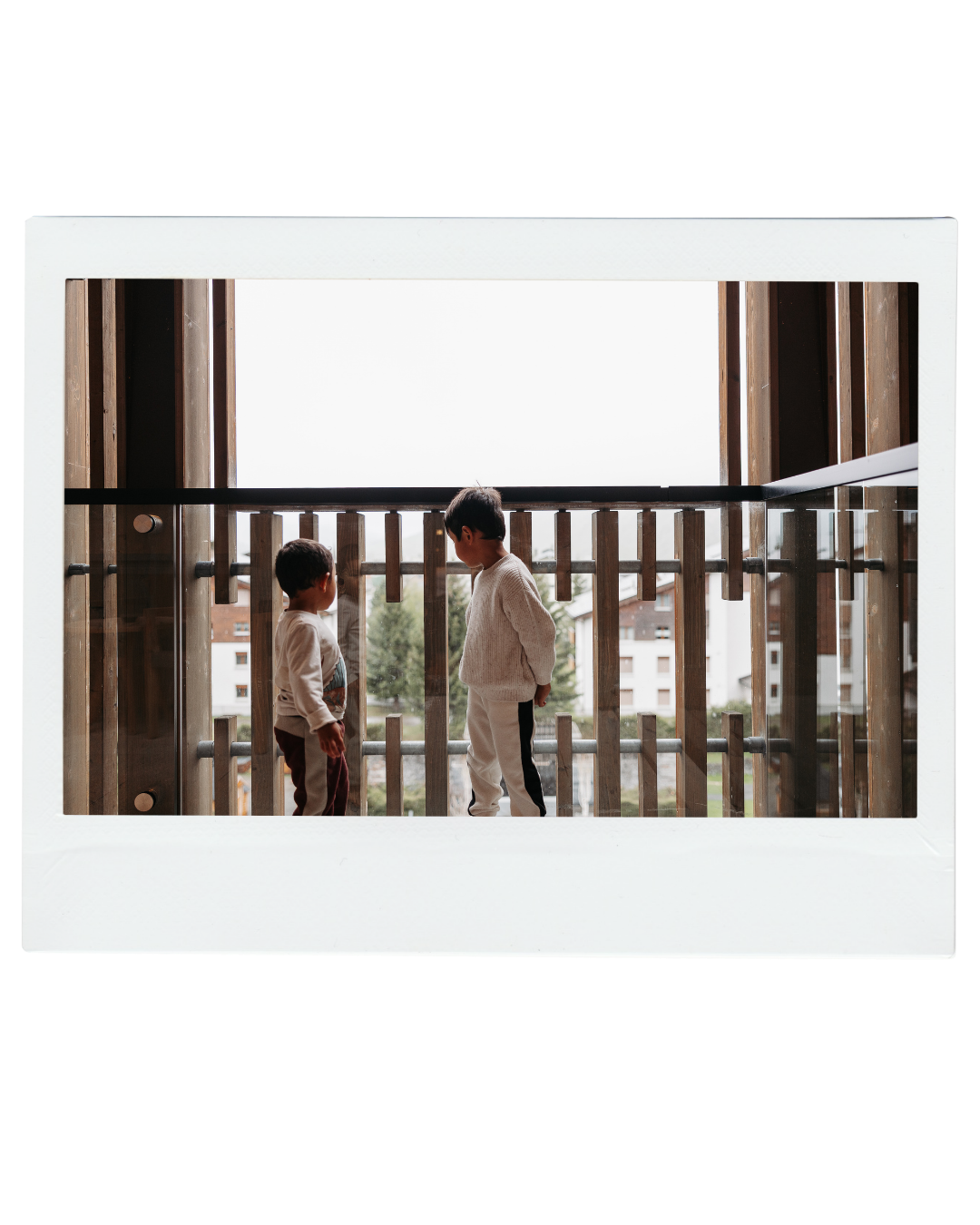 Two children face each other on a balcony in soft natural light, Polaroid-style photo.  | Karina Thomson Photography Raleigh NC