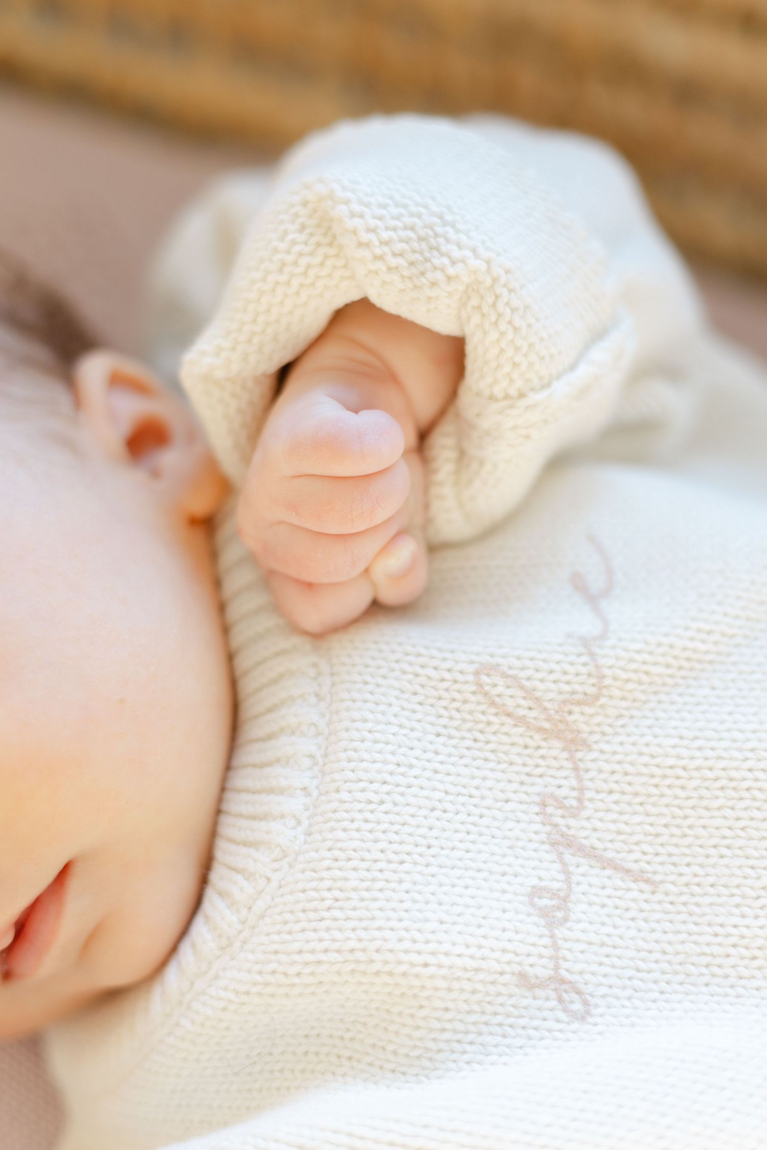 Close-up of a sleeping newborn baby's tiny fist clutching a soft white knit blanket.  | Karina Thomson Photography Raleigh NC
