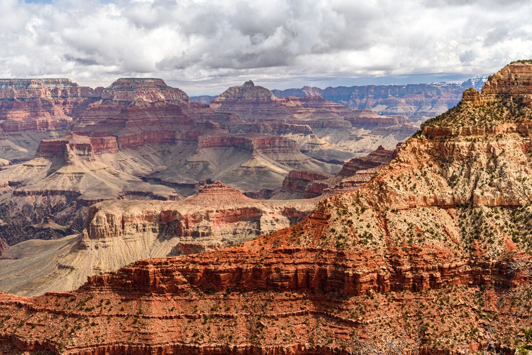 Stunning aerial view of the Grand Canyon's layered red rock formations under a dramatic cloudy sky.