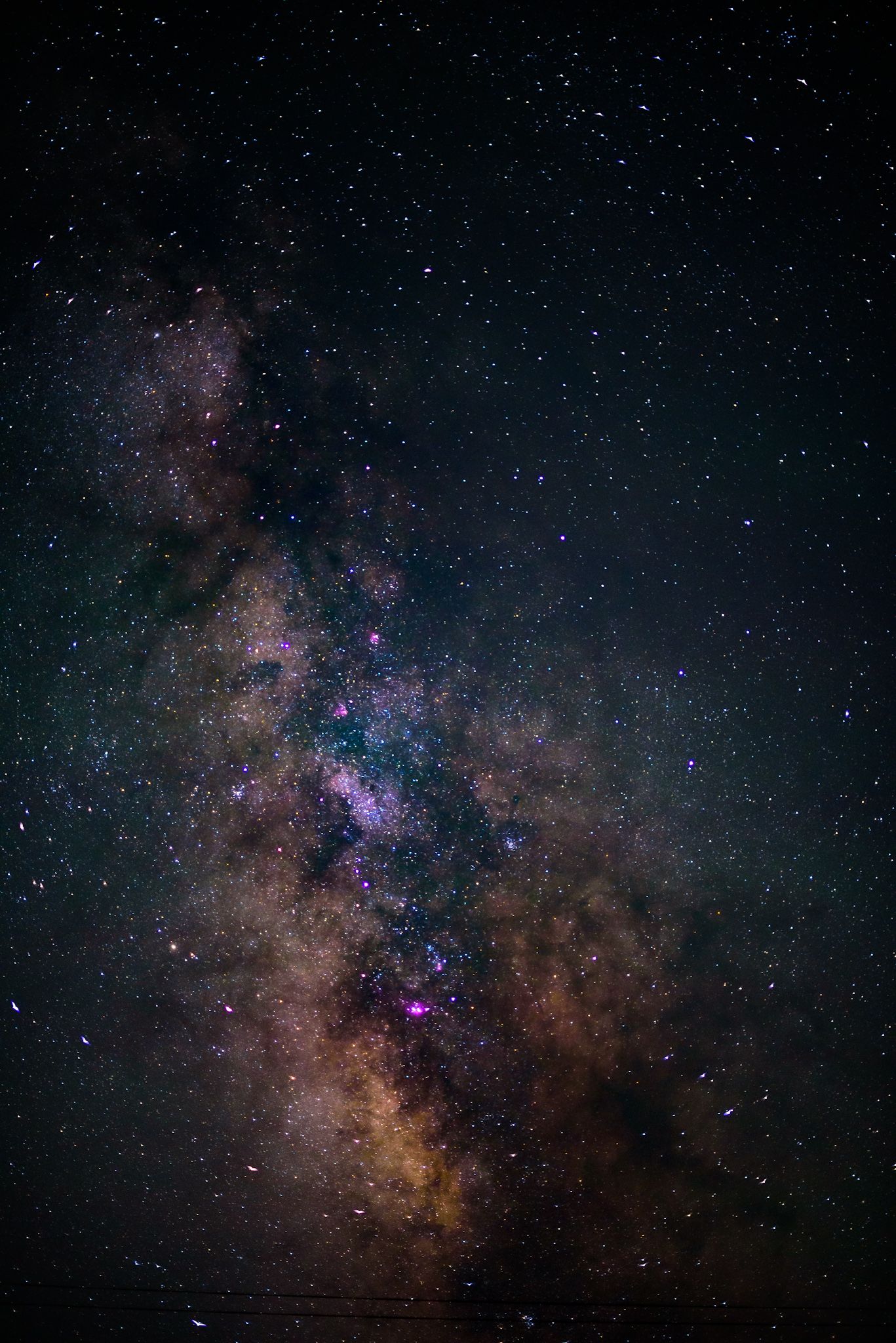 Stunning Milky Way galaxy with vibrant purple and gold hues illuminating a star-filled night sky.