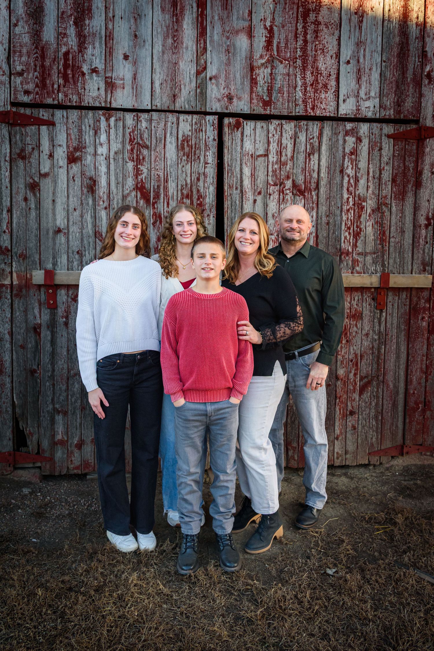 Family of five posing in front of a rustic red barn door outdoors. Polk County, NE