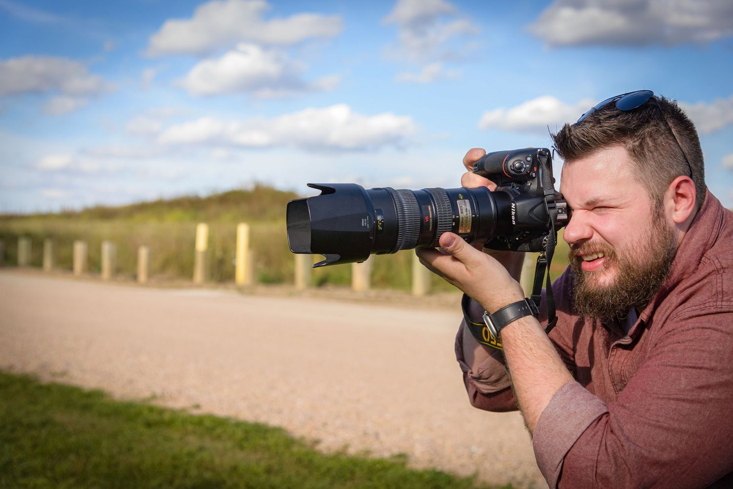 Bearded man photographing outdoors with a professional DSLR camera and telephoto lens. York, NE