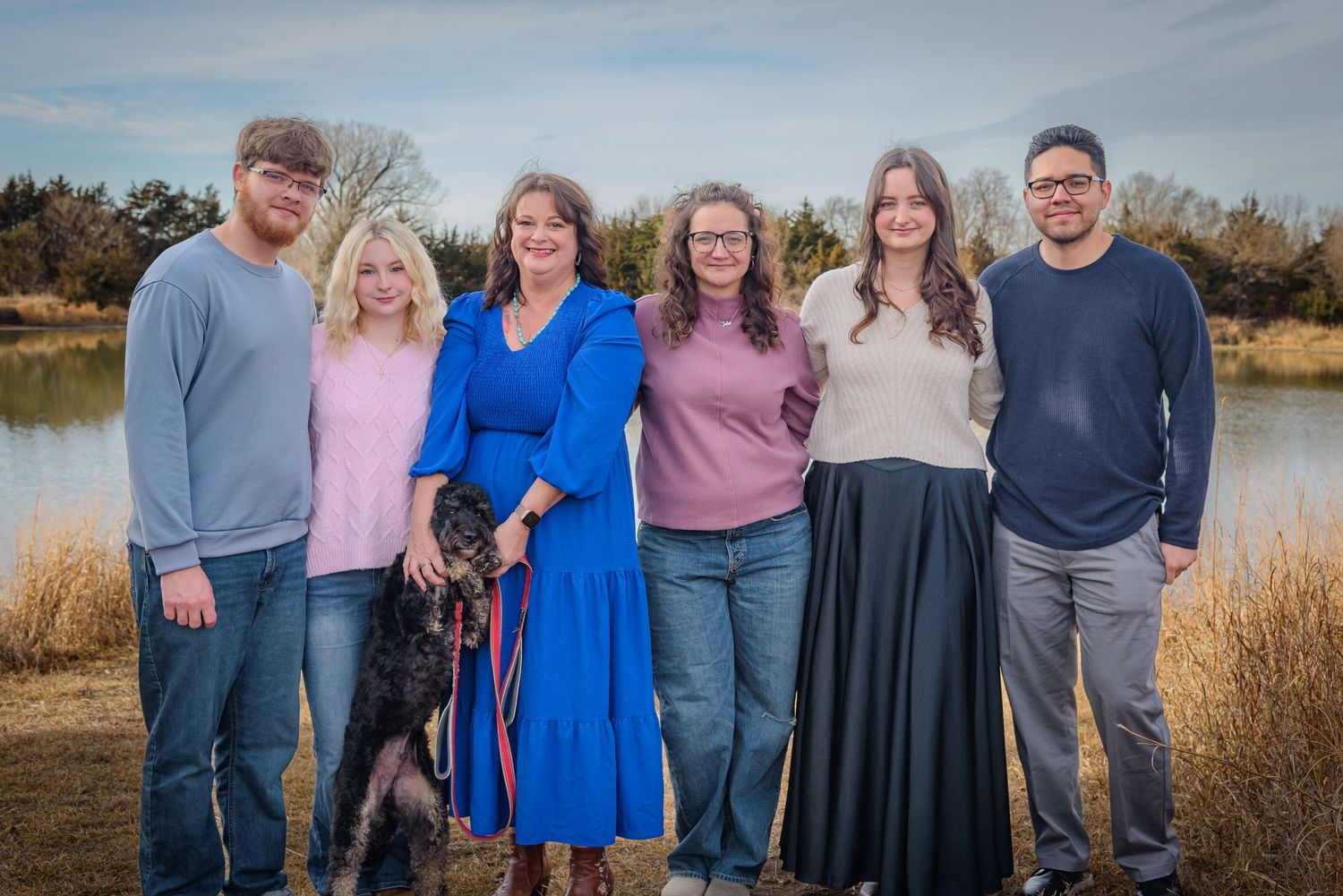 Family of six with black dog posing together outdoors near a lake in autumn. York, NE
