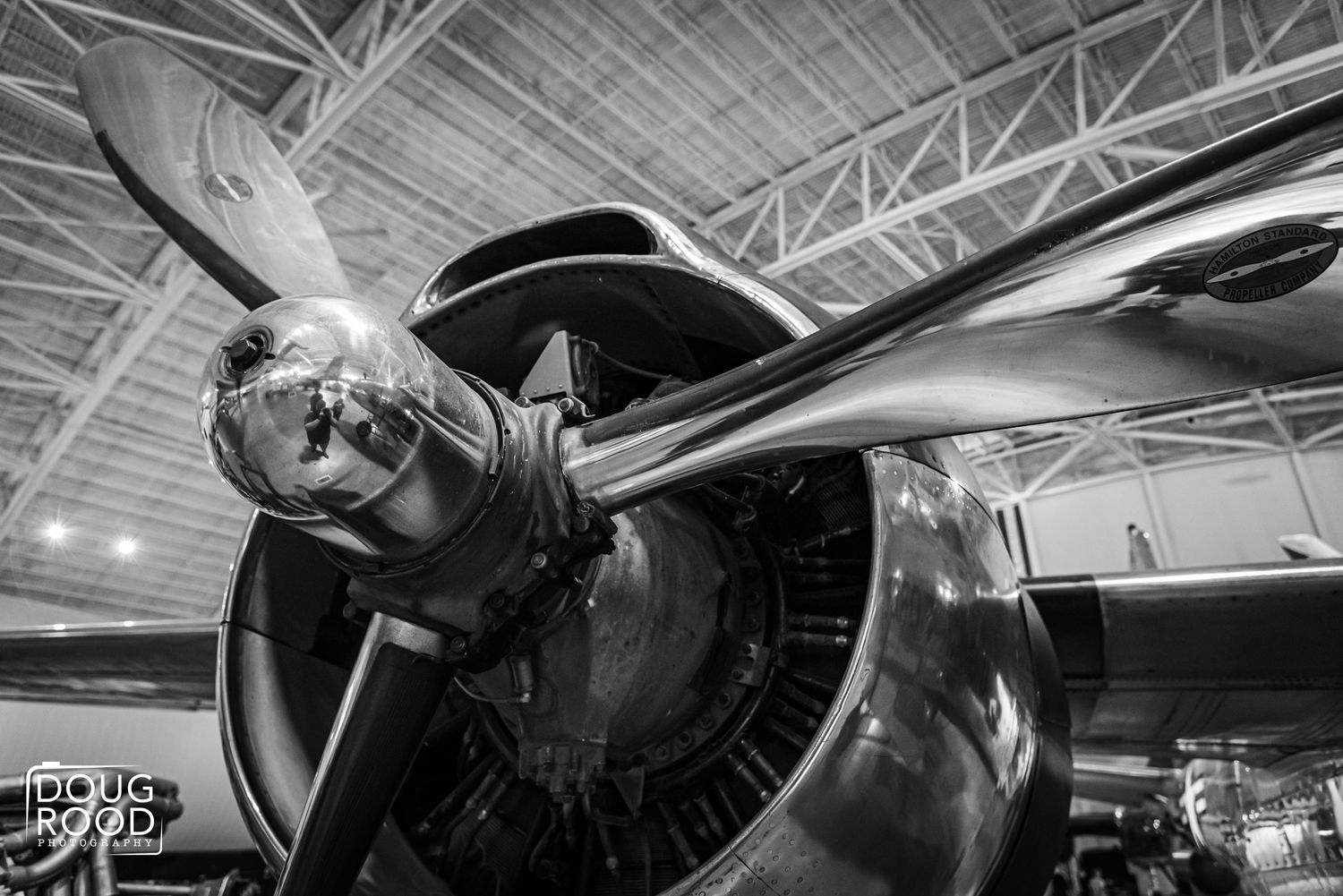 Black and white close-up of a vintage aircraft propeller and radial engine inside a hangar.