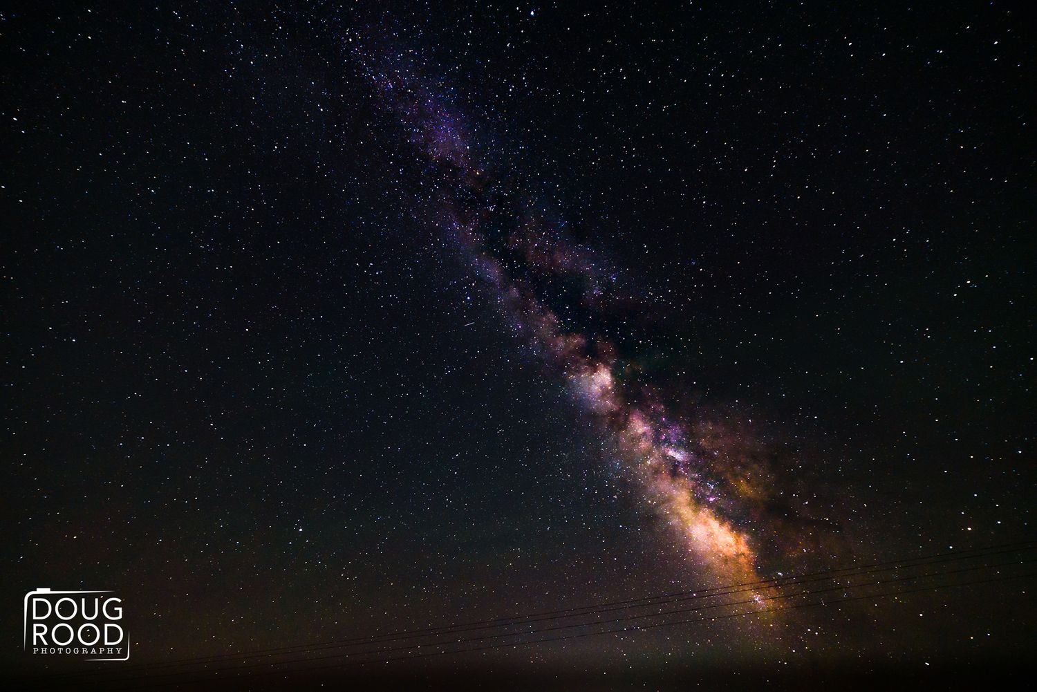 Stunning Milky Way galaxy arc over dark horizon with vibrant purple and orange star clusters in night sky.