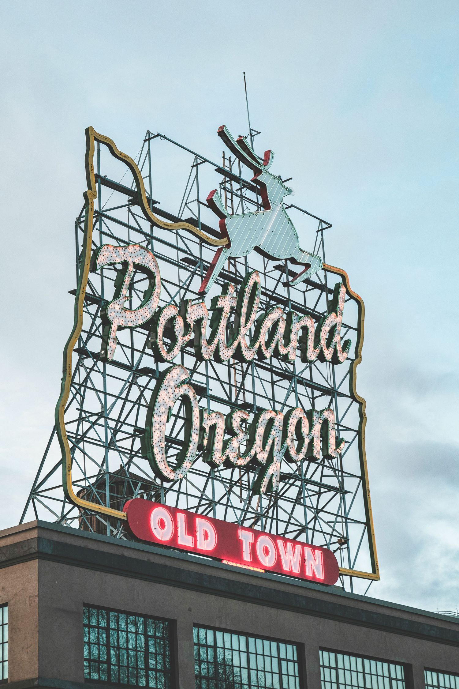 Iconic Portland Oregon Old Town neon sign mounted on a brick building against a cloudy sky.